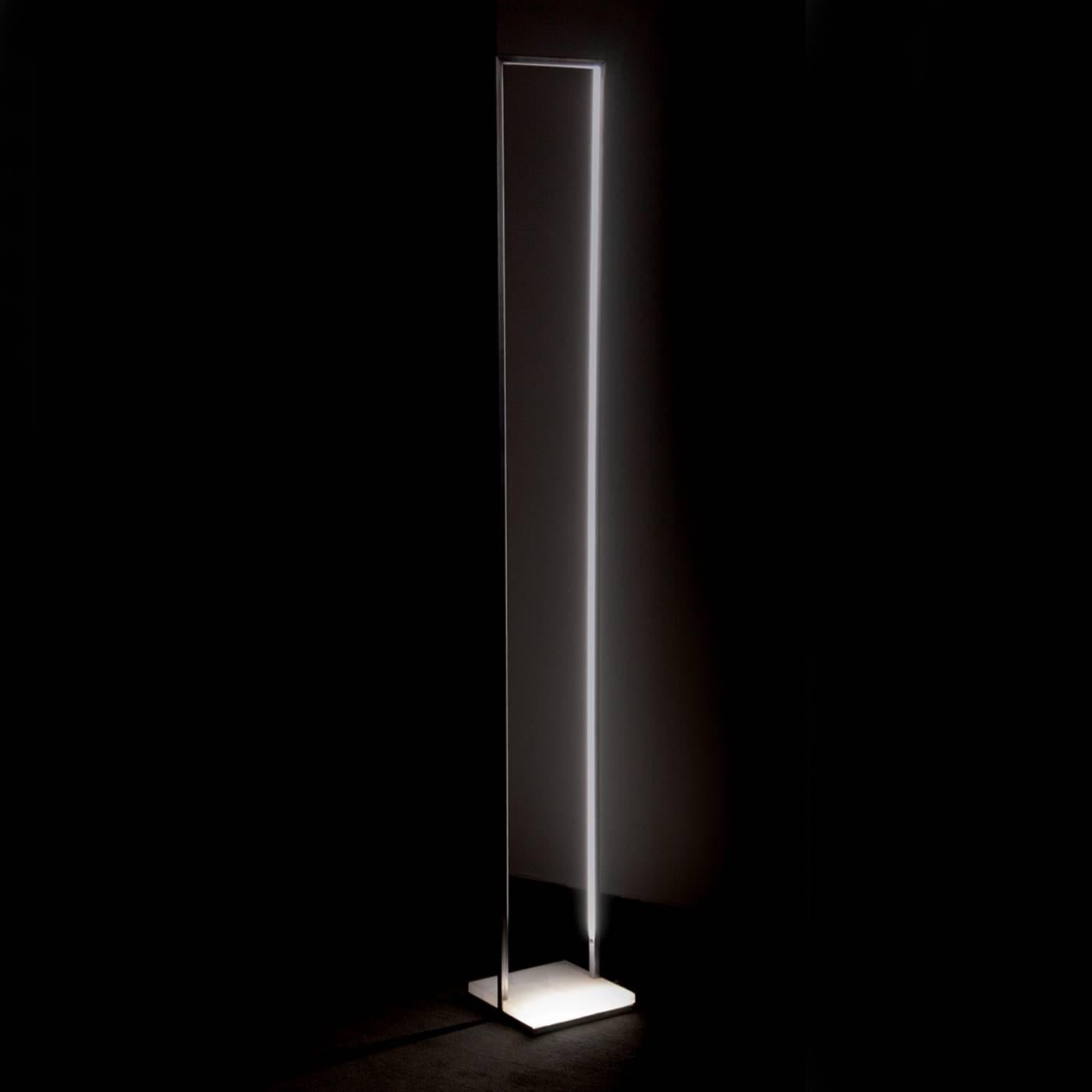 Striking and modern, this exquisite lamp rests on a square of white onyx stone and its structure, entirely made in iron bars with a square section, forms an elegantly elongated rectangle that evokes the shape of a tall and narrow window. On the