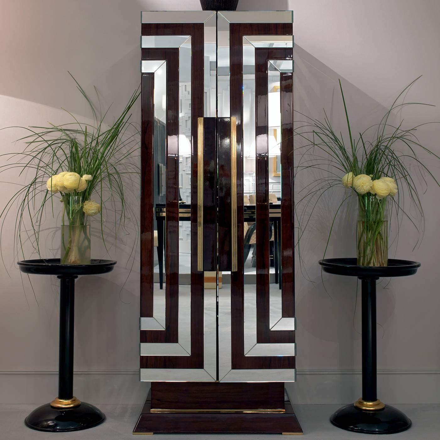 This exquisite bar cabinet is inspired by the bold and sophisticated style of Art Deco, with its geometric volumes and decorations, and its polished reflective surfaces. The glossy walnut wood structure is adorned with a series of concentric lines