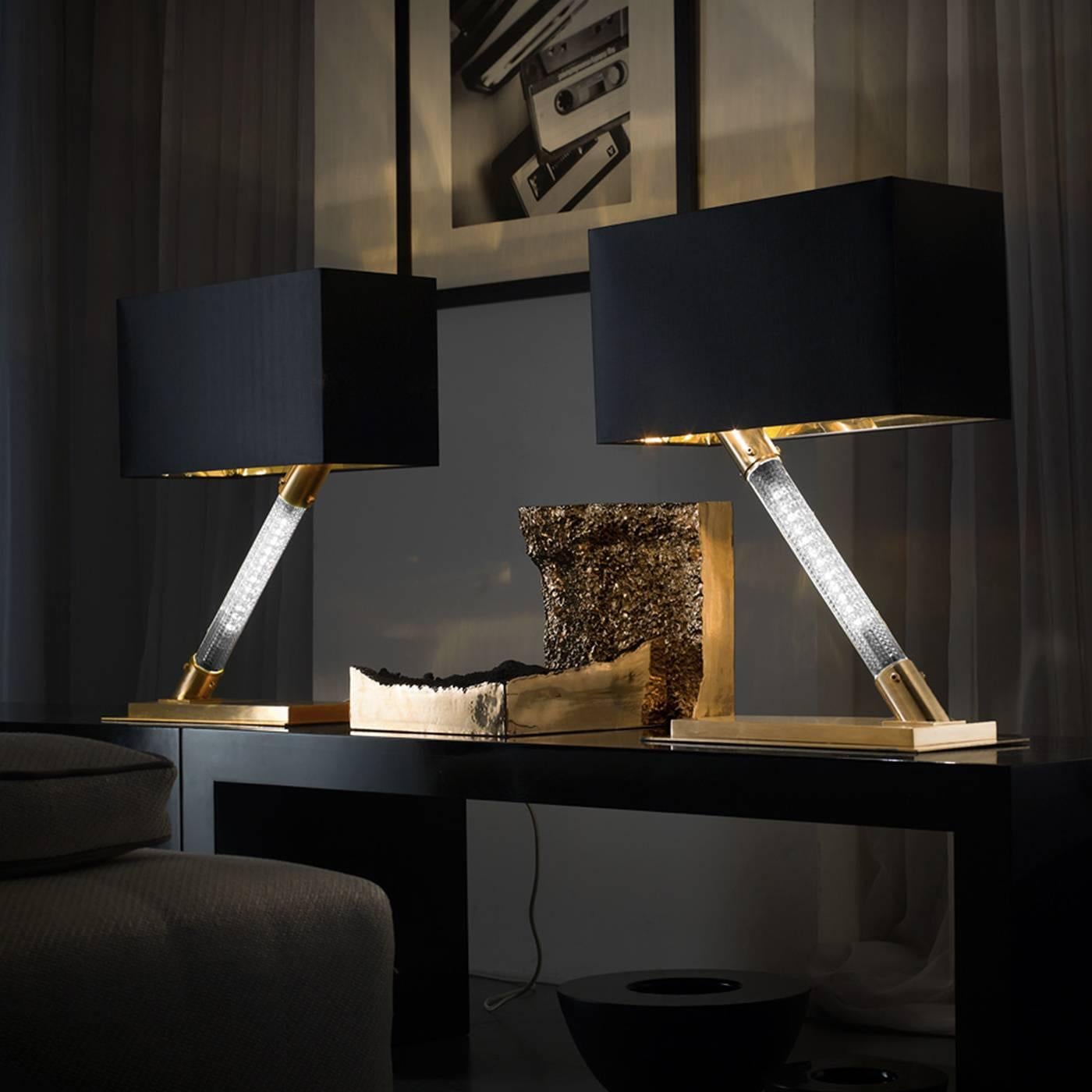 This lamp features a unique central structure featuring a Z-shape, crafted using a brushed brass element as the base topped with a central cylindrical crystal element, which was hand-engraved, containing the light. The details are also in brushed