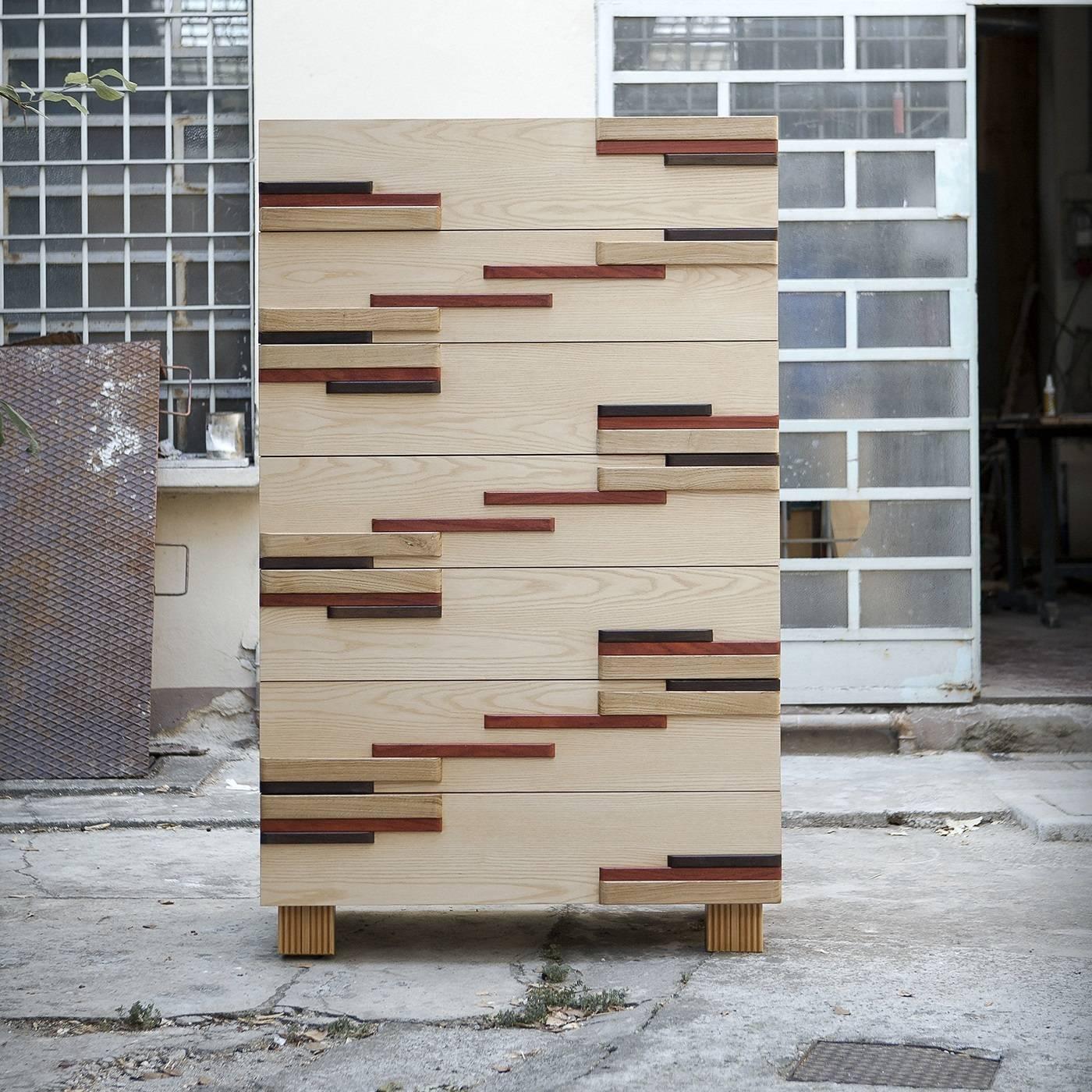 This unique chest of drawers is sure to make a statement in any decor, particularly if made of contemporary pieces. Its seven front panels are adorned with geometric elements arranged as a sort of music staff made of different woods whose colors and