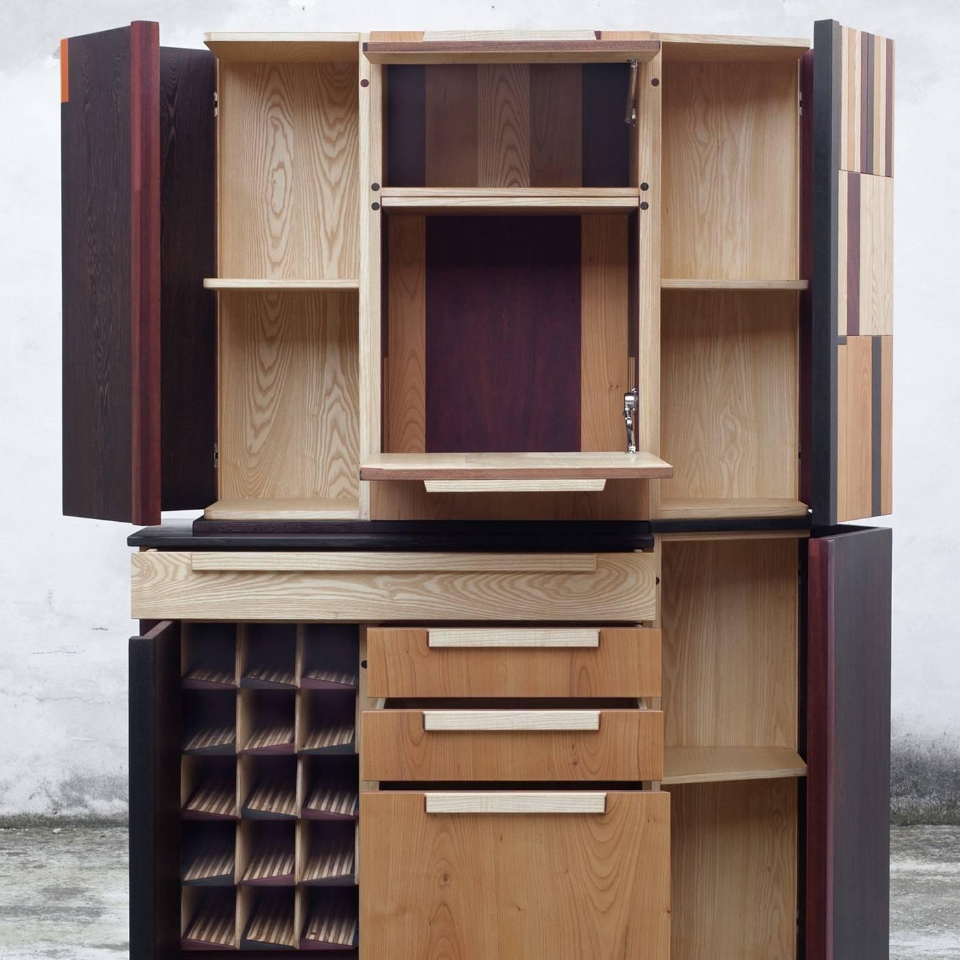 This TOTEM is a piece of functional design, thanks to its many spaces that can contain a variety of objects. Inside, there are six compartments for glasses, a cart for liqueurs, a bottle-rack, and two drawers: one for silverware, the other for