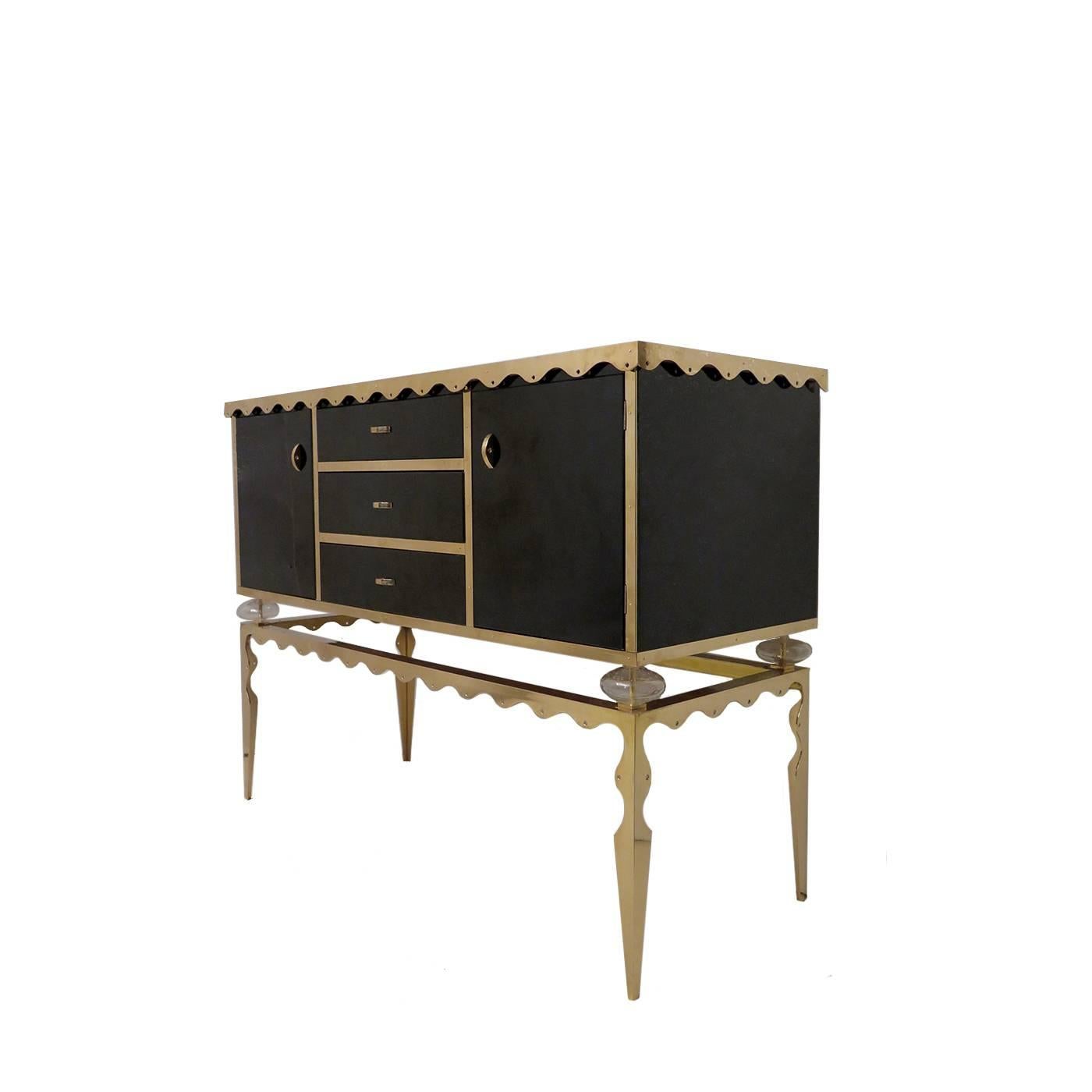 Inspired by the French Art Deco style, this sideboard features a body entirely covered in glass with a striking black coloration. The front is divided into two side doors and three central drawers. The black of the piece is elegantly paired with the