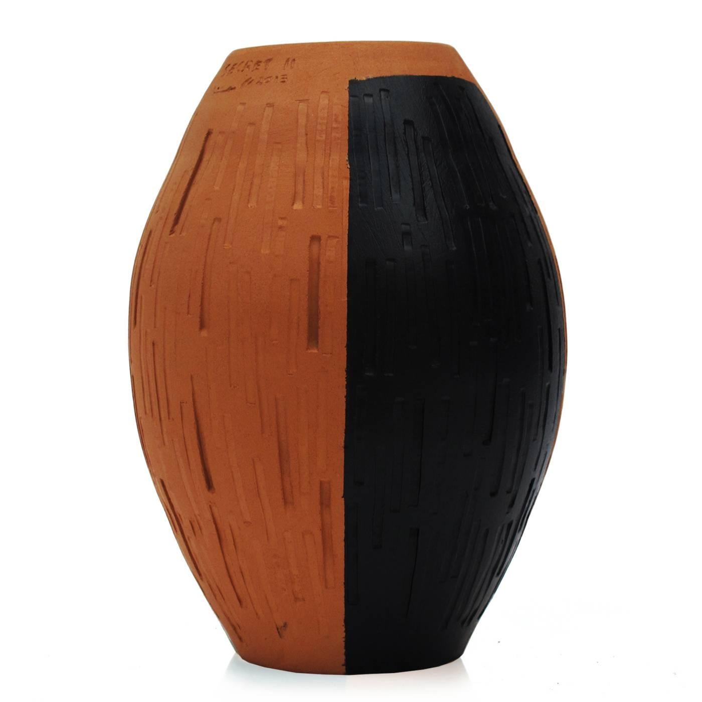 This exquisite vase is part of the Secret collection. Its oval shape is gentle and elegant, while the striking black and orange color combination gives the piece a modern allure, as does the unique texture that digs straight and round grooves onto