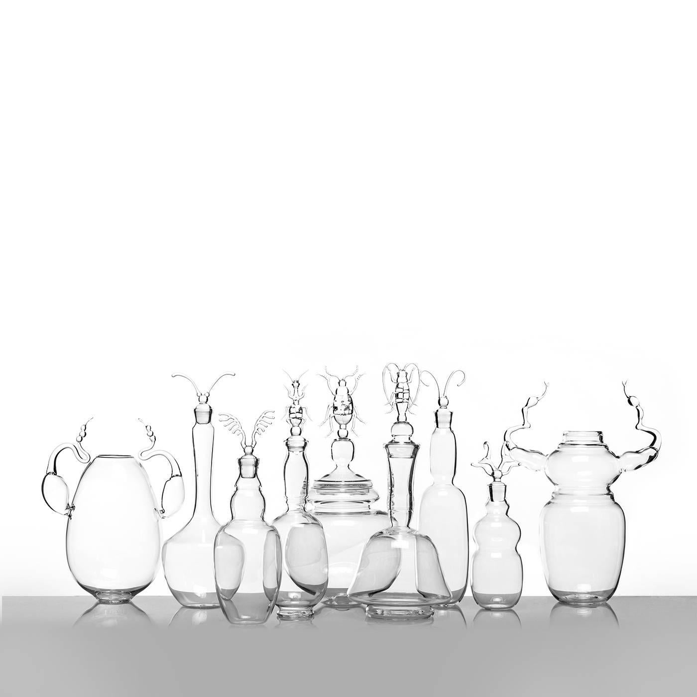 This exquisite decanter was entirely mouth-blown and handmade of borosilicate glass and is part of a limited edition of only 29 pieces. Its sinuous shape, resting on a small plinth base, is inspired by the Silhouette of a specific beetle, the