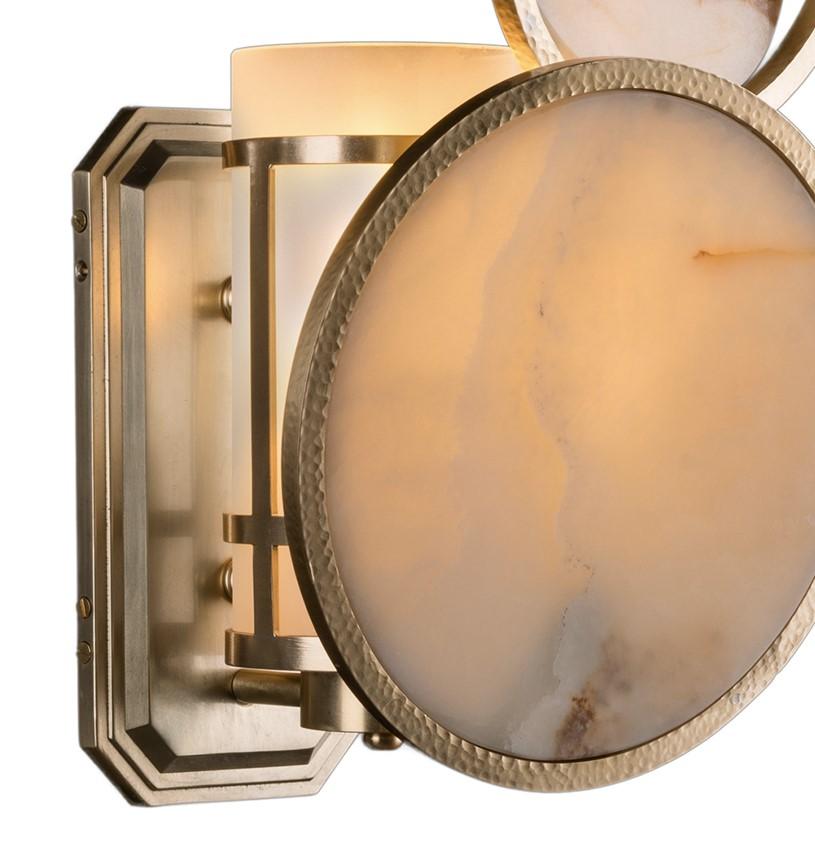 Evoking the phases of the moon, this alluring wall sconce will infuse timeless elegance into any modern decor. The piece features a celestial motif composed of a central onyx circle adorned with a smaller circular element and a tilted brass ring. A