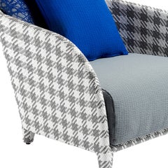 Sillón de exterior con estampado de tartán gris y cojines azules, diseñado por Paola Navone