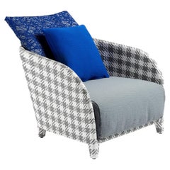 Sillón de exterior con estampado de tartán gris y cojines azules, diseñado por Paola Navone