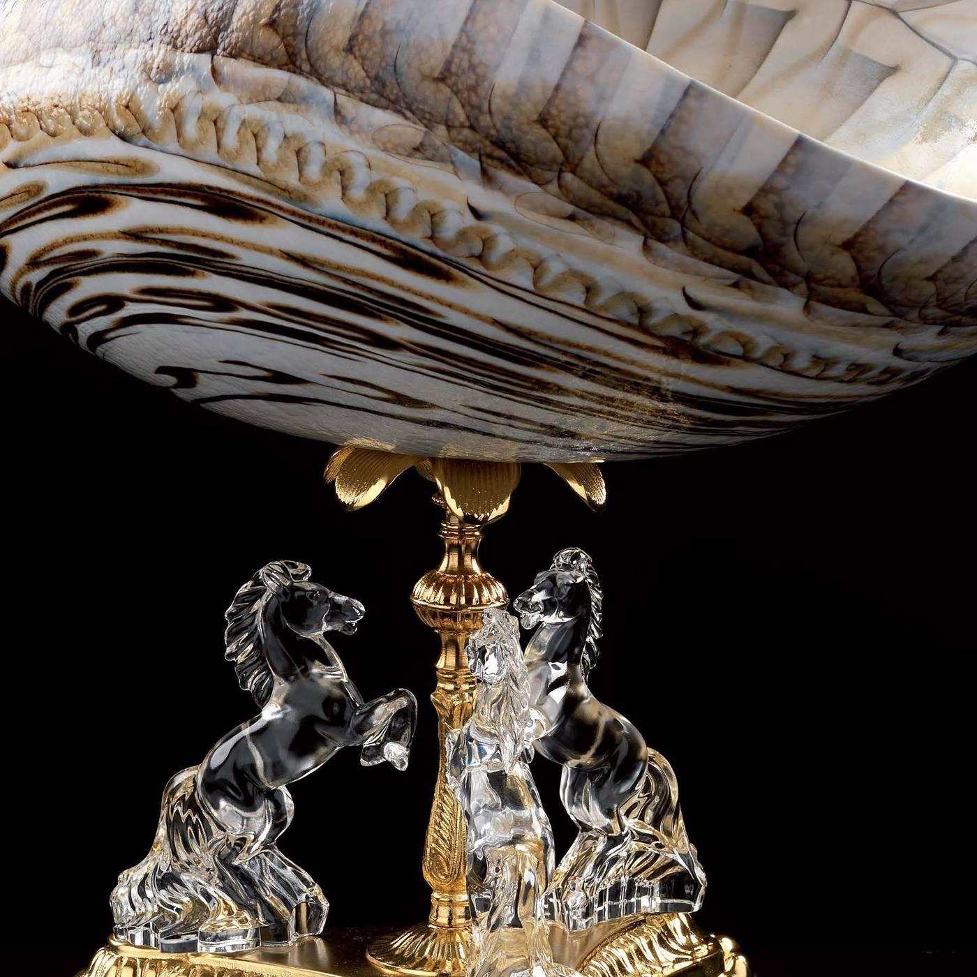 This centerpiece has a striking appearance and is constructed from three main components. The base and stand are in 24-karat gold-plated brass. Sitting on top of the base is a decoration featuring three horses exquisitely crafted entirely in clear