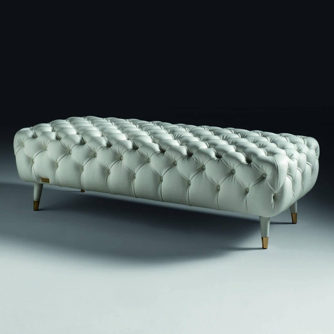 This exquisite ottoman in spruce and beechwood has padding in polyurethane foam. The elegant white cover is not removable and can be in button-padded fabric or leather. The feet are covered in polished brass.