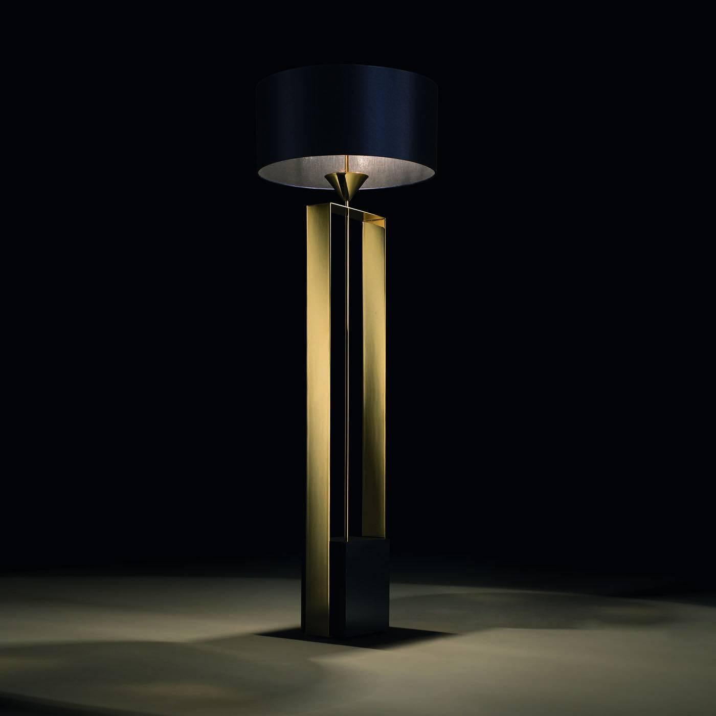 This elegant floor lamp projects its light downward. It has a structure in wood with a polished finish in dark blue. Vertical, gold-polished metal elements elongate the body of the lamp. The lampshade is in the same dark blue nuance of the body.