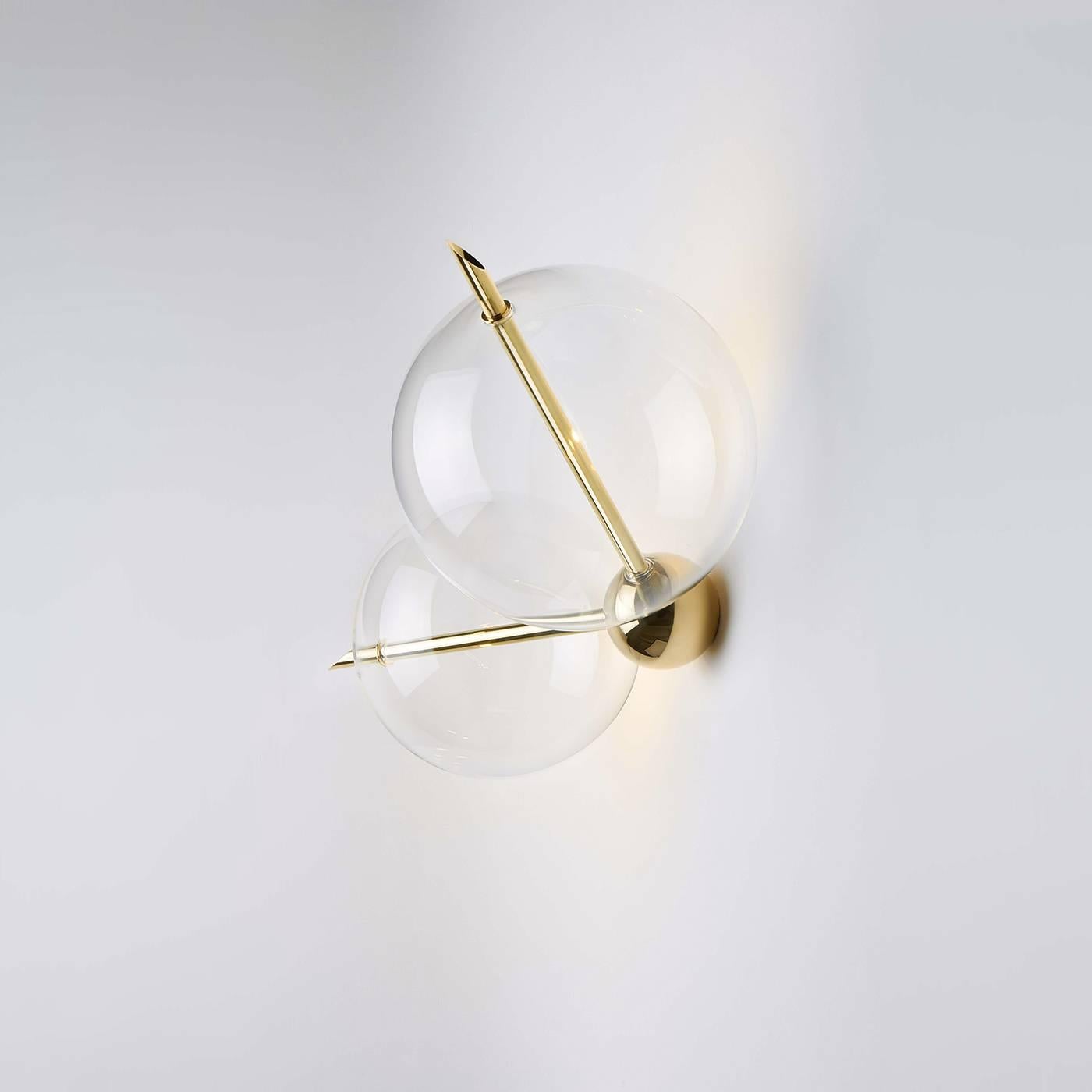 This exquisite two-light sconce can be displayed alone, or paired with a twin to illuminate the sides of a bed or of a mirror, or it can be used among others from the same 'Lune' collection, inspired by planets and their satellites. The brass