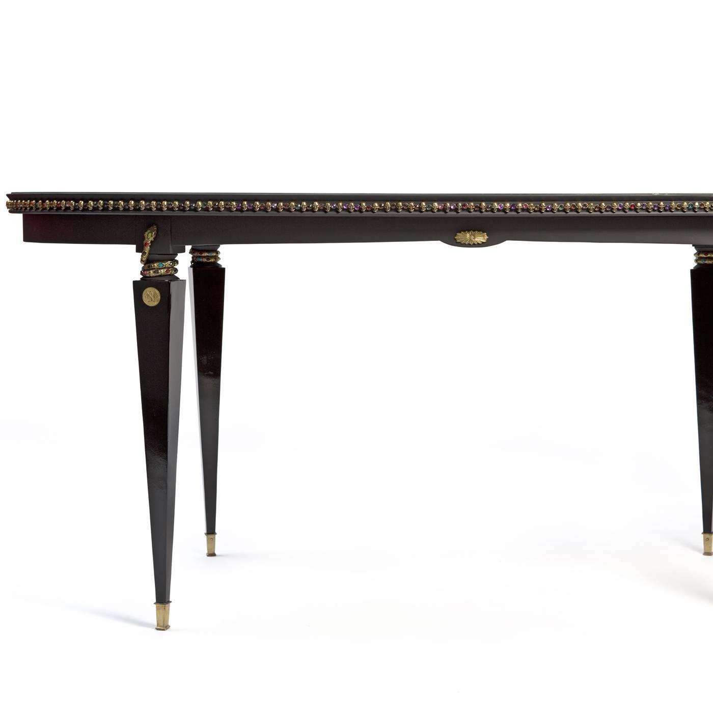This wooden table was crafted in the 1950s and was restored with luxurious accents, such as the gold lace adorning the top, covered with its original glass panel. The legs are playfully decorated with colorful snakes wrapped around the upper part,