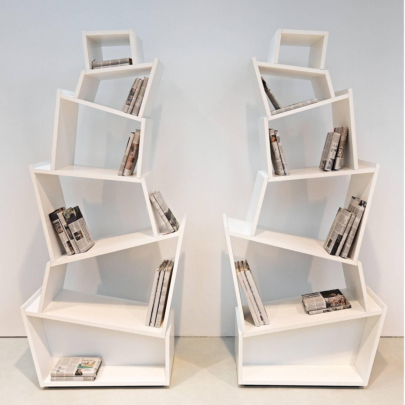 A visually striking bookcase that revolutionizes the traditional design with a new perspective. The open double-sided frame is made of fir with a matte white lacquered finish and features six slanted shelves in ascending order of size. Alternating