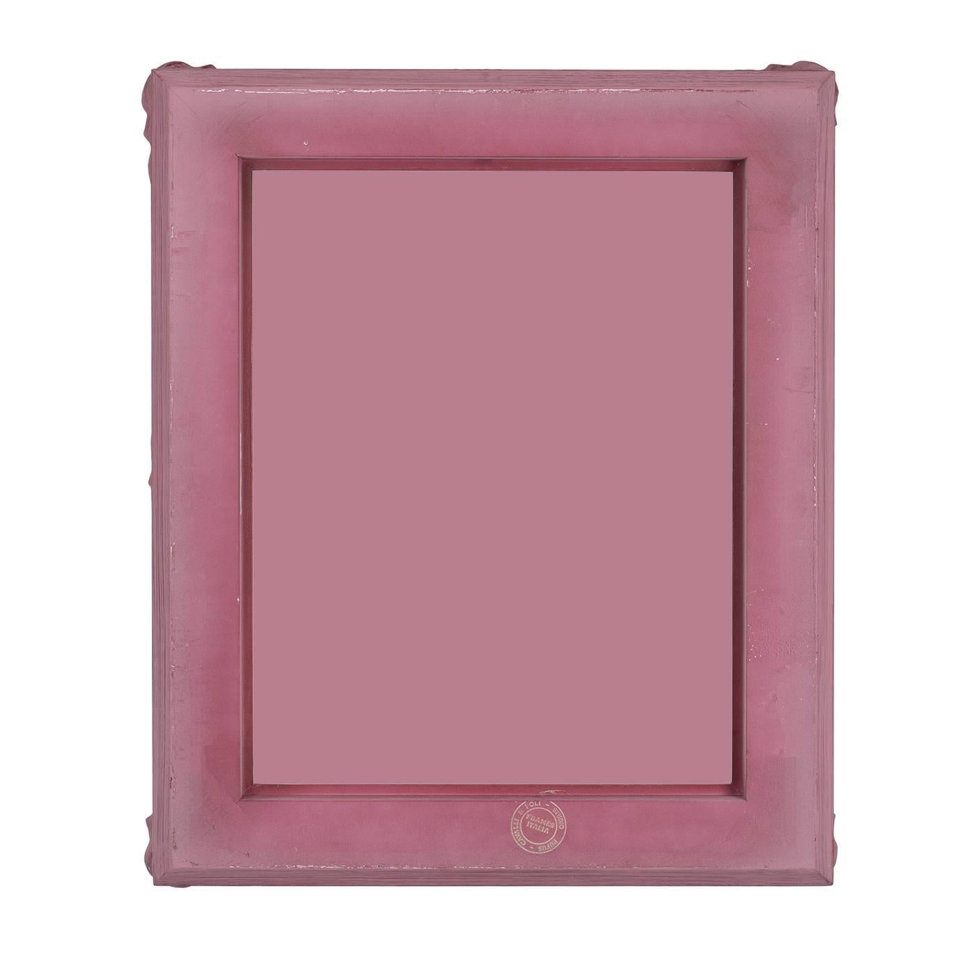 A mirror with understated elegance and splendor, highlighted by a distinct pink finish and a crowned profile featuring embellished floral details in 