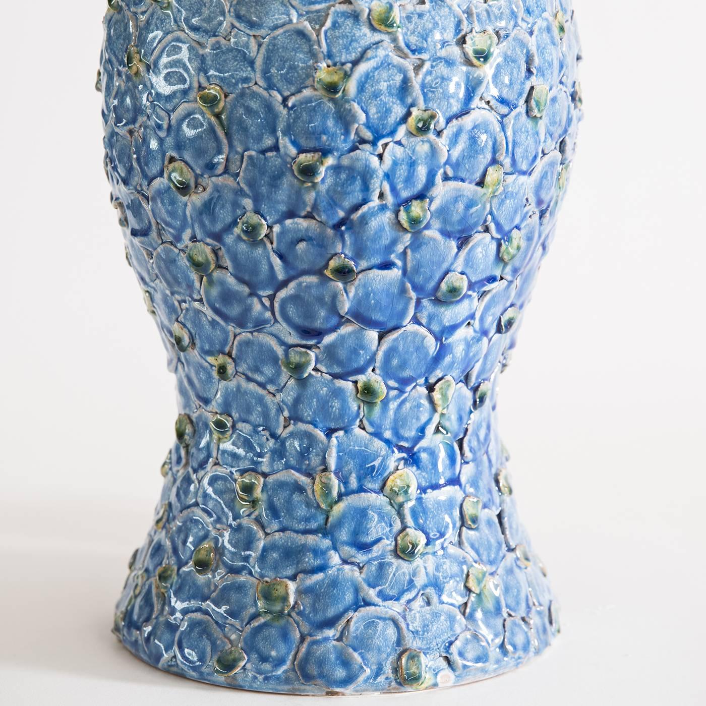 Maiolica table lamp consummately handcrafted by the master potters of the Tuscan ceramic atelier ND Dolfi. This elegant lamp is characterized by the relief pattern of light blue flowers running uninterruptedly throughout the maiolica piece.