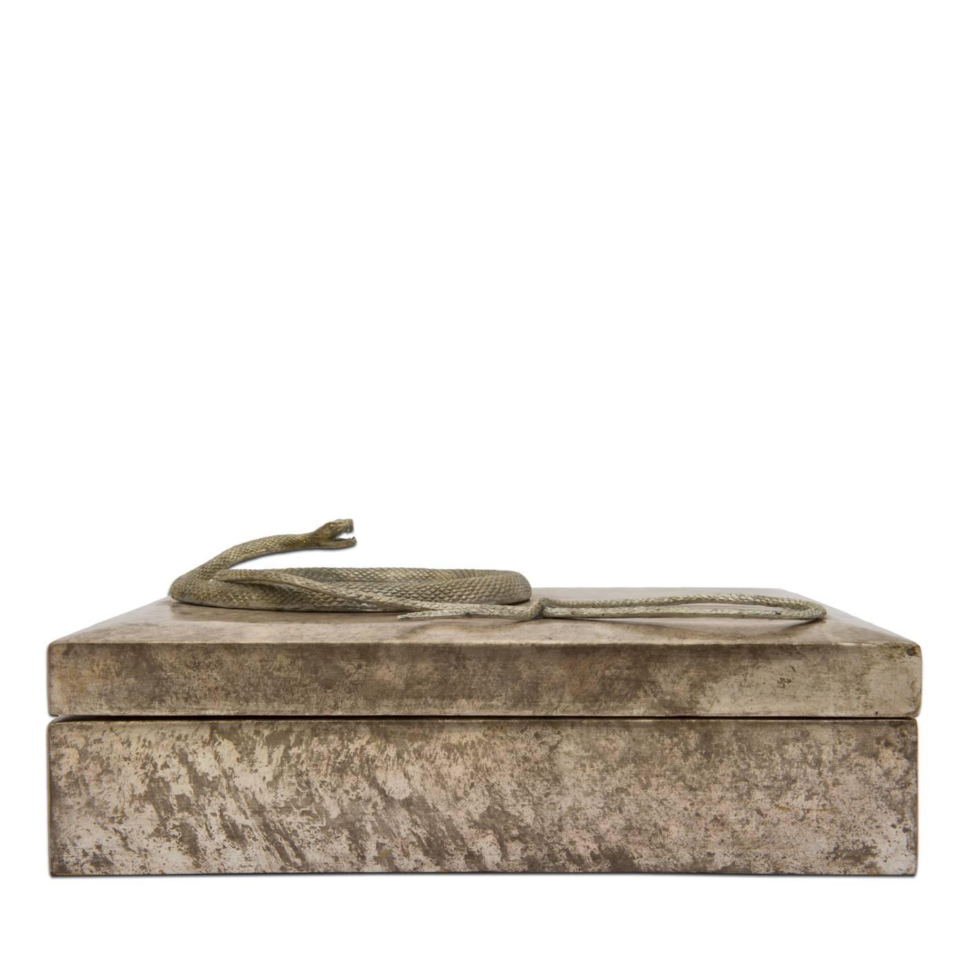 This is an effulgent wooden case in silver leaf finish by Neapolitan designer Bottiglieri. The lid is adorned with the glimmering form of an uncoiling snake, representing the life energy of light. Originally the piece was designed for a coffee-table.