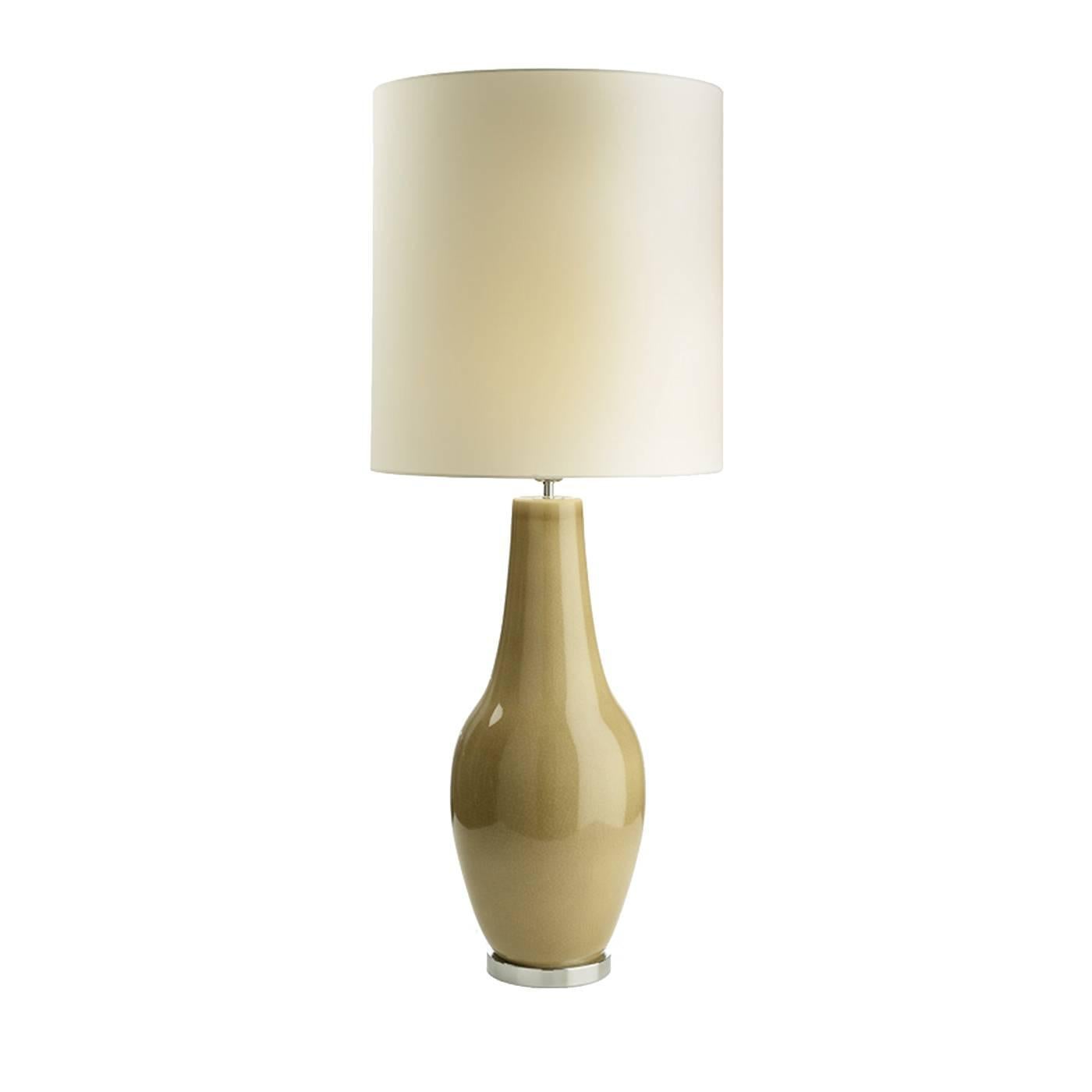 Crafted entirely of ceramic, the structure of this elegant table lamp is elongated and charming, in a delicate shade of beige and with a crackle glaze finish. Resting on a metal round base, this piece is completed with a fabric shade and will be a