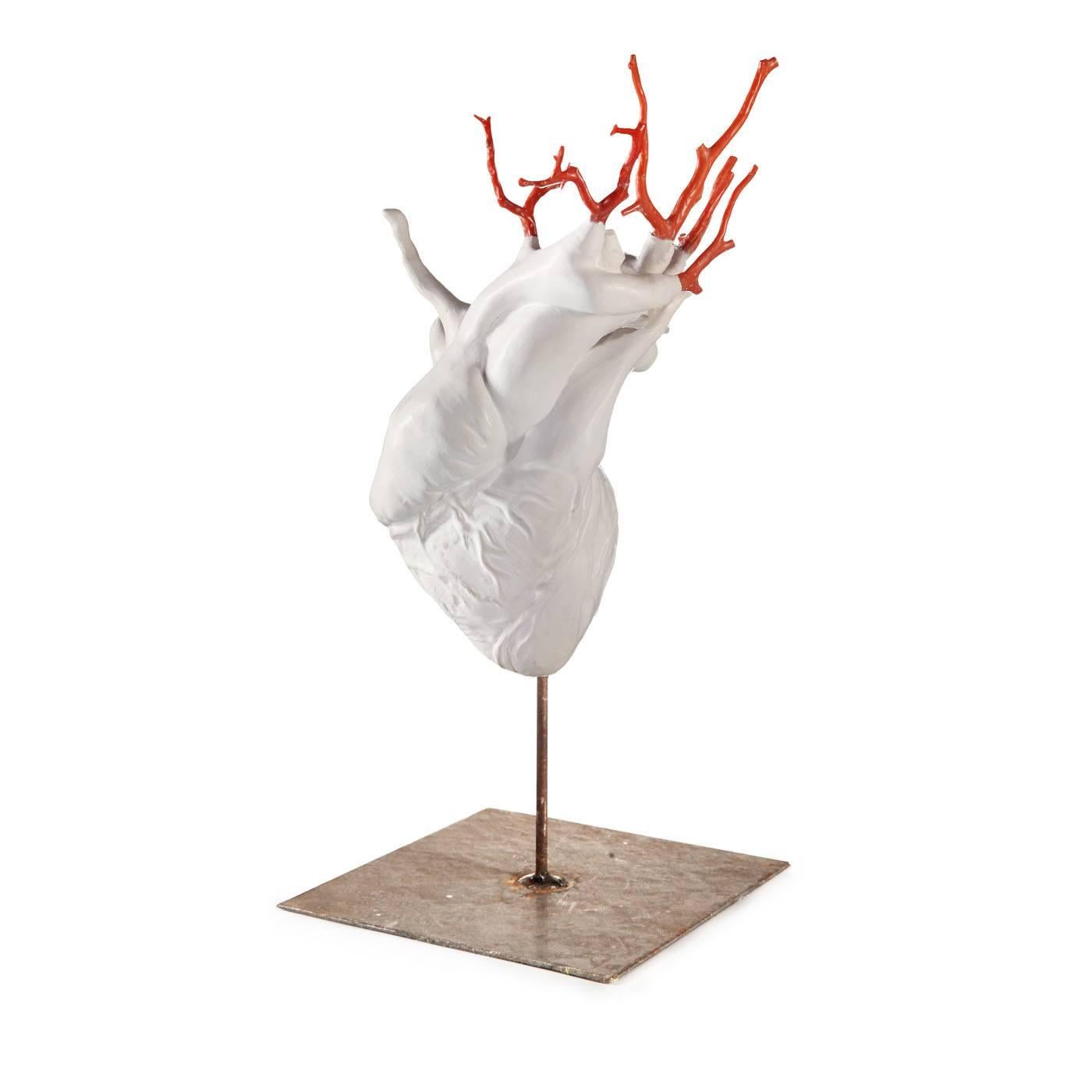 A white heart-shaped sculpture with terracotta coral tree branches jutting out on top, depicting arteries and veins which suggest the idea of man’s union with nature through art, made with miscellaneous materials and a rough surface.