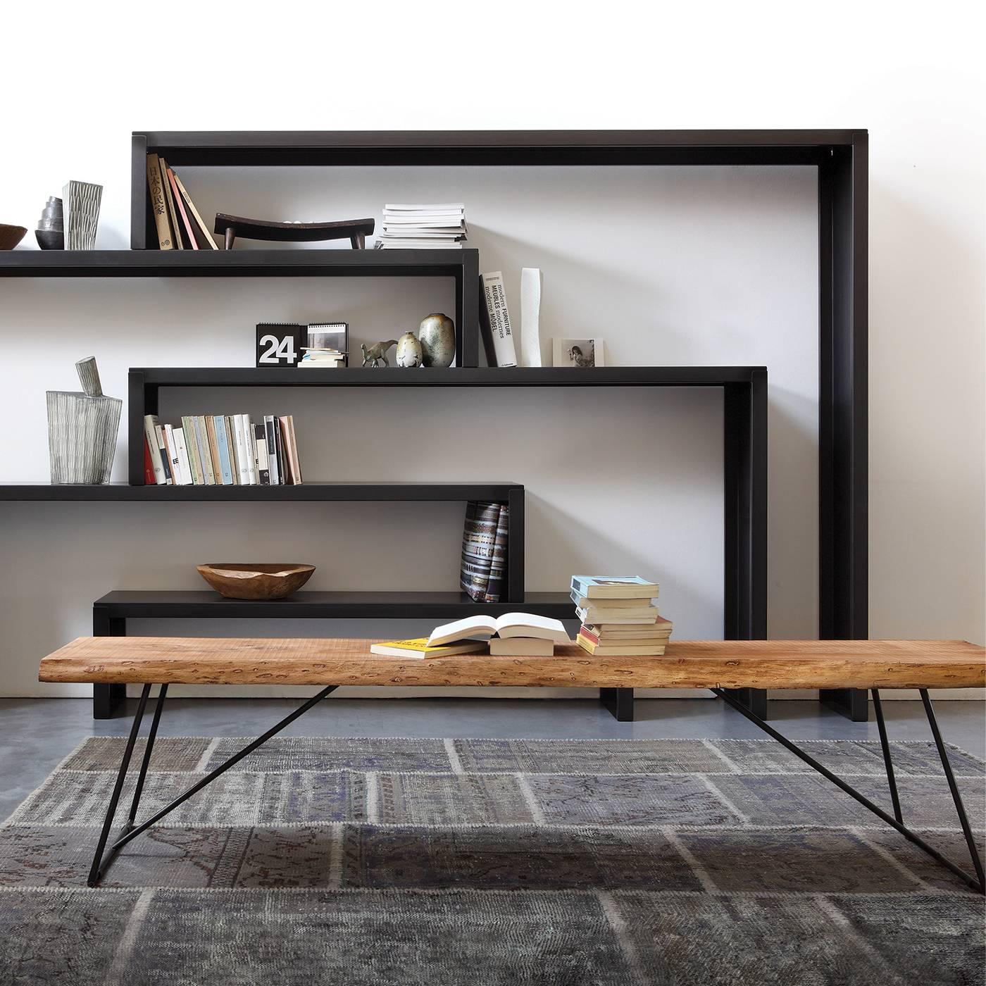 This elegant yet rustic bench has a slim metal supporting structure with black powder coating. The top is solid, aged olive wood, with a wax polish and natural, raw edges. This piece is one-of-a-kind.