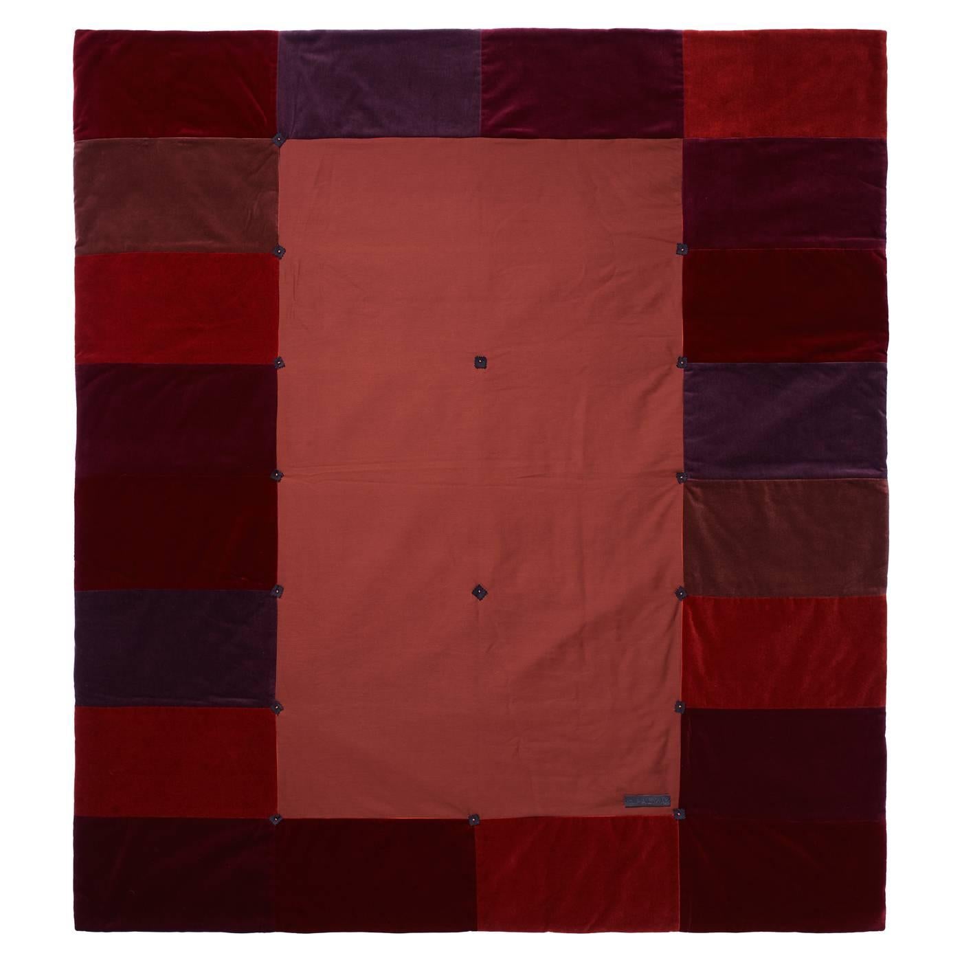 This striking throw will make a magnificent addition to a modern living room, thanks to its warm color palette in different tones of red and the bold, geometric decorations of its front. Remarkably soft, this piece is made of cotton velvet with a