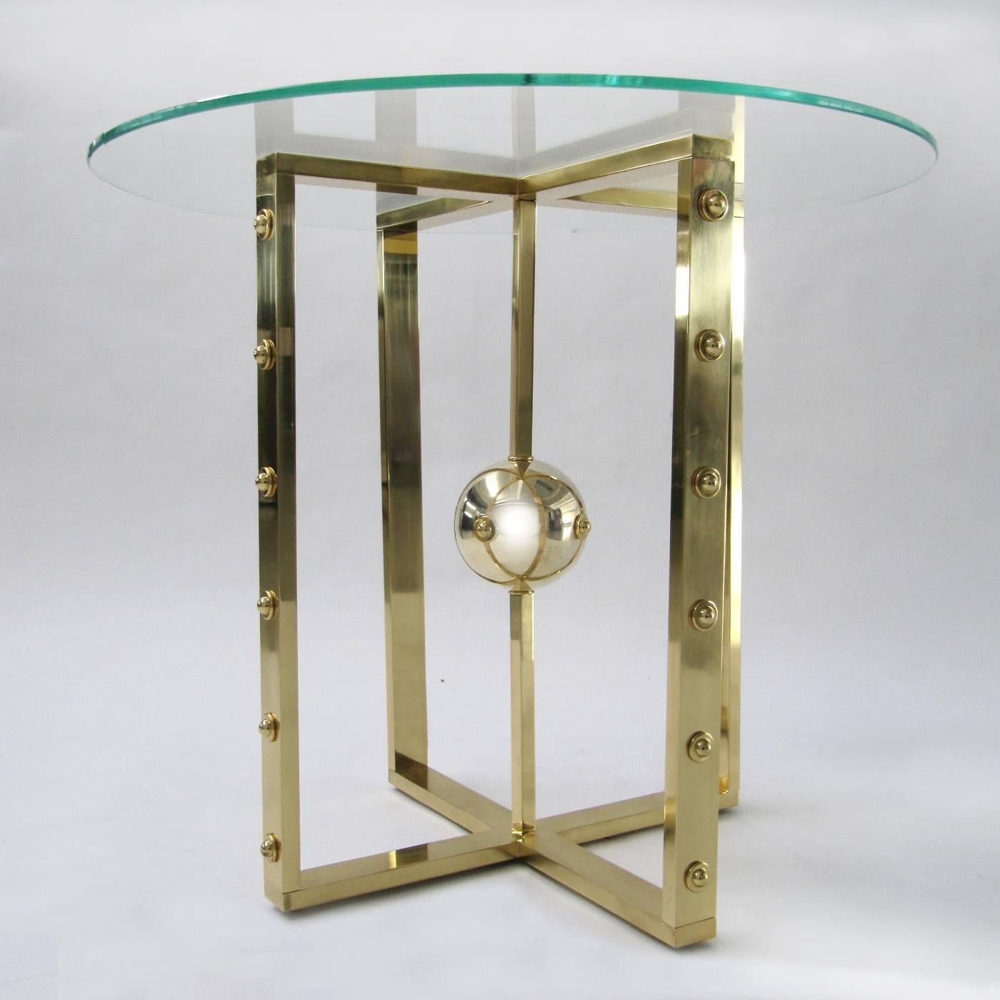 This elegant table is inspired by the structure of the atom and features a brass structure that has been brushed by hand and finished with a protective transparent treatment. The top is in hardened glass.