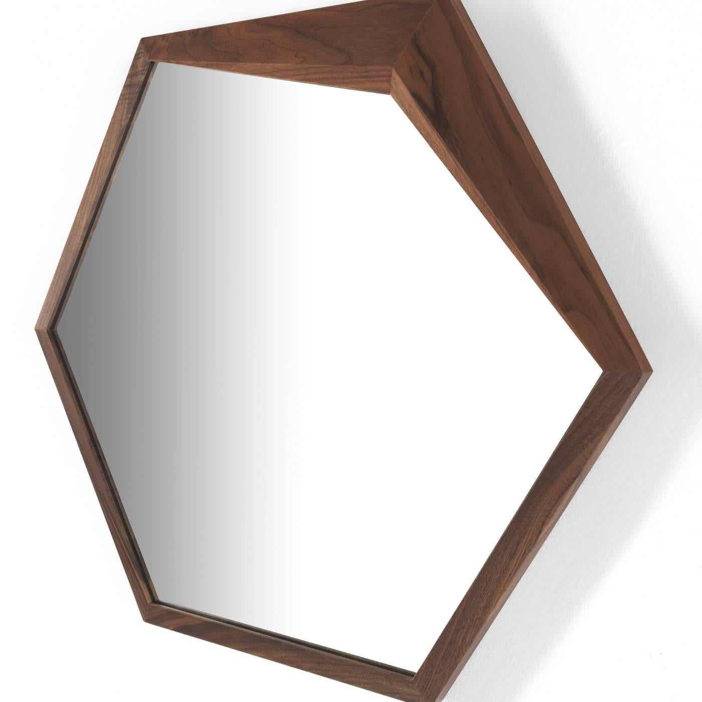 Die minimalistische Form dieses sechseckigen Spiegels wird von einer exquisiten Struktur aus massivem Nussbaumholz umrahmt, die in einer ihrer Ecken, wo das Holz dicker wird, einen charmanten Akzent setzt und diesem zeitlosen, funktionalen
