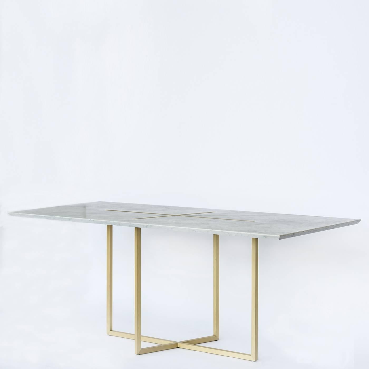 This exquisite dining table features a top of solid white Carrara marble with a striking decoration of two brass lines crossing at its center. The top rests on a structure of solid brushed brass.
