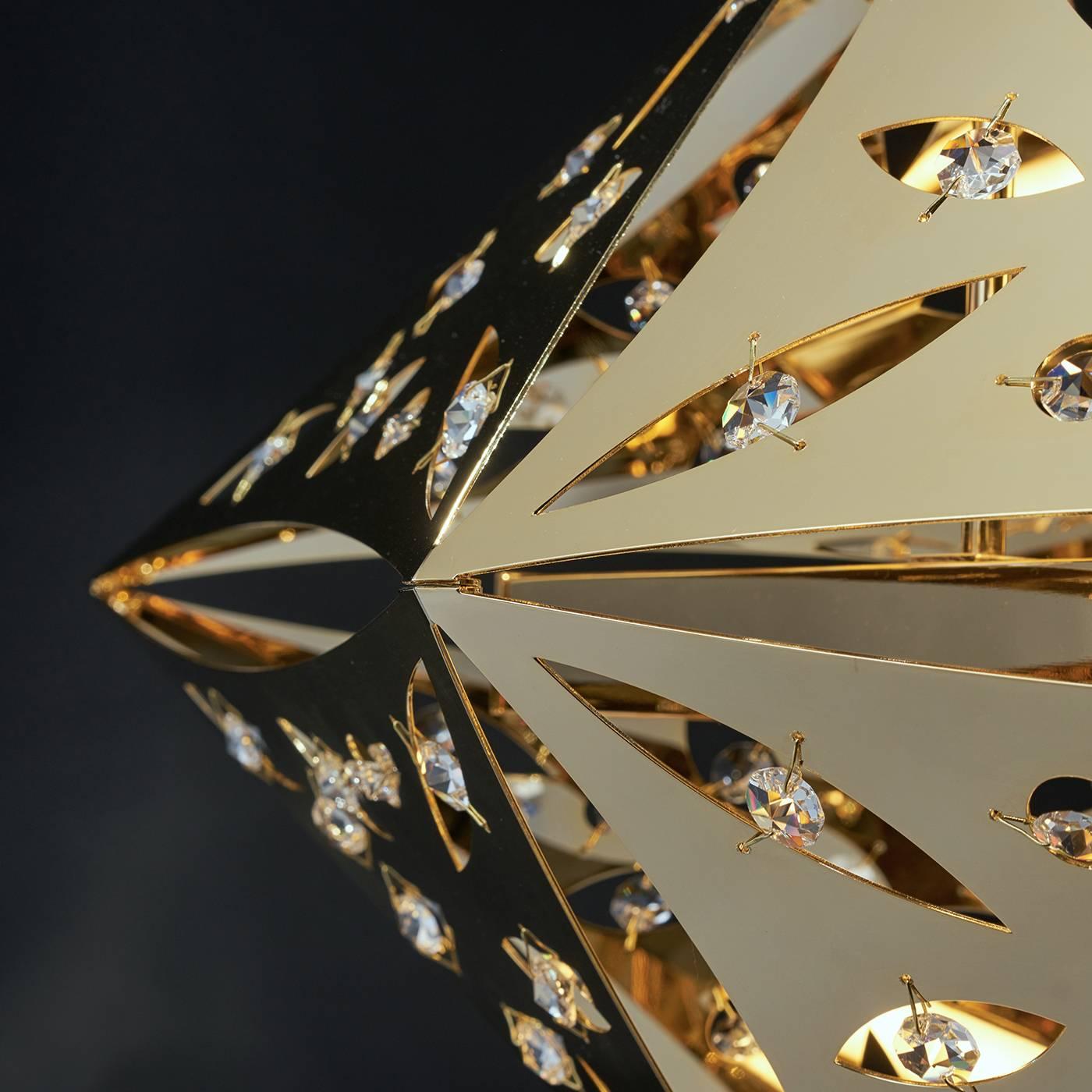 This chandelier is a contemporary statement piece designed by Alessandro Mognato. A stainless steel diamond-shaped element with a precious 24k gold cover features several holes that frame crystal octagons reflecting the light coming from underneath.