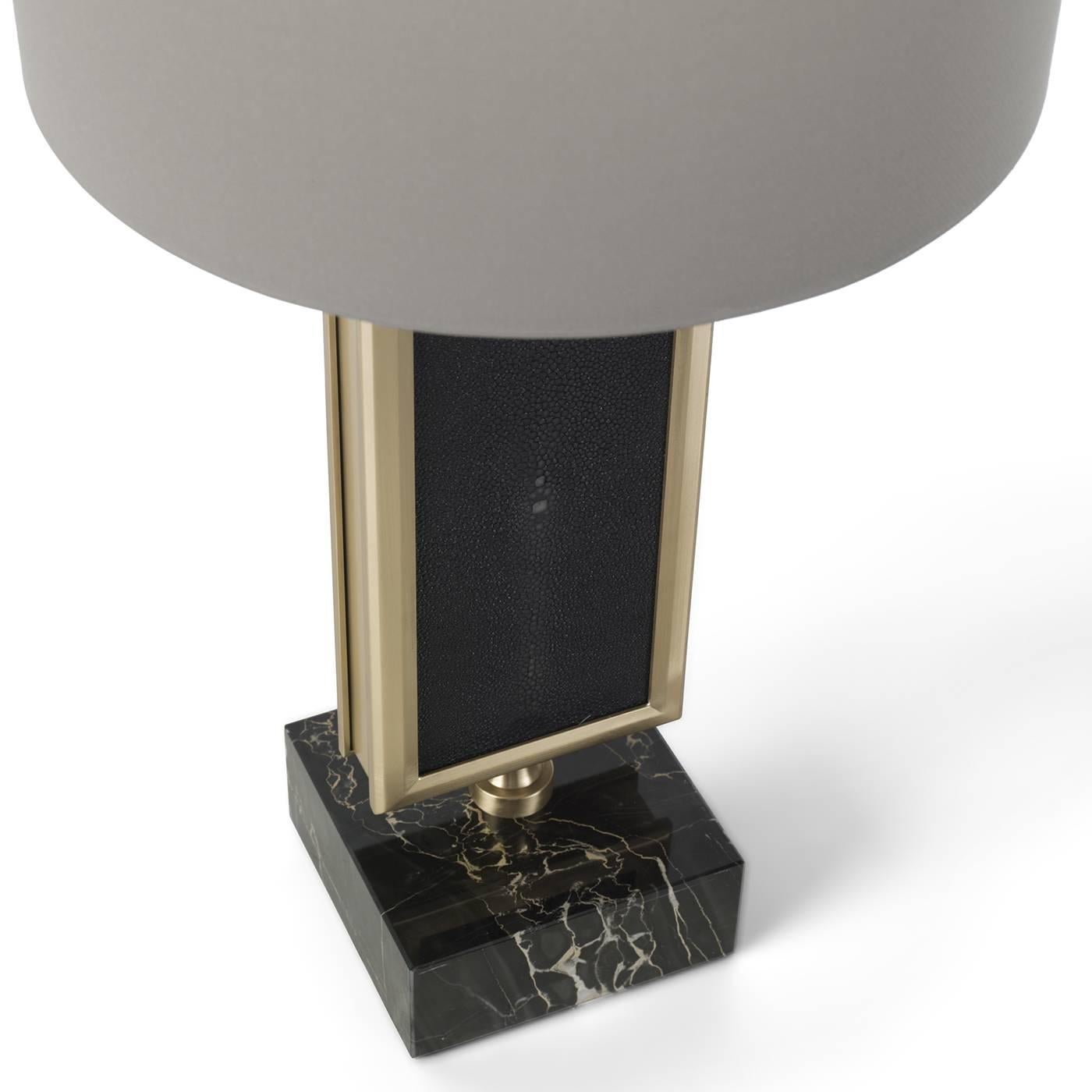 This sophisticated table lamp features noble materials and traditional craftsmanship combined with a contemporary design, for a timeless and elegant final effect that will make a statement in any decor. The base is a cube of Portoro marble that