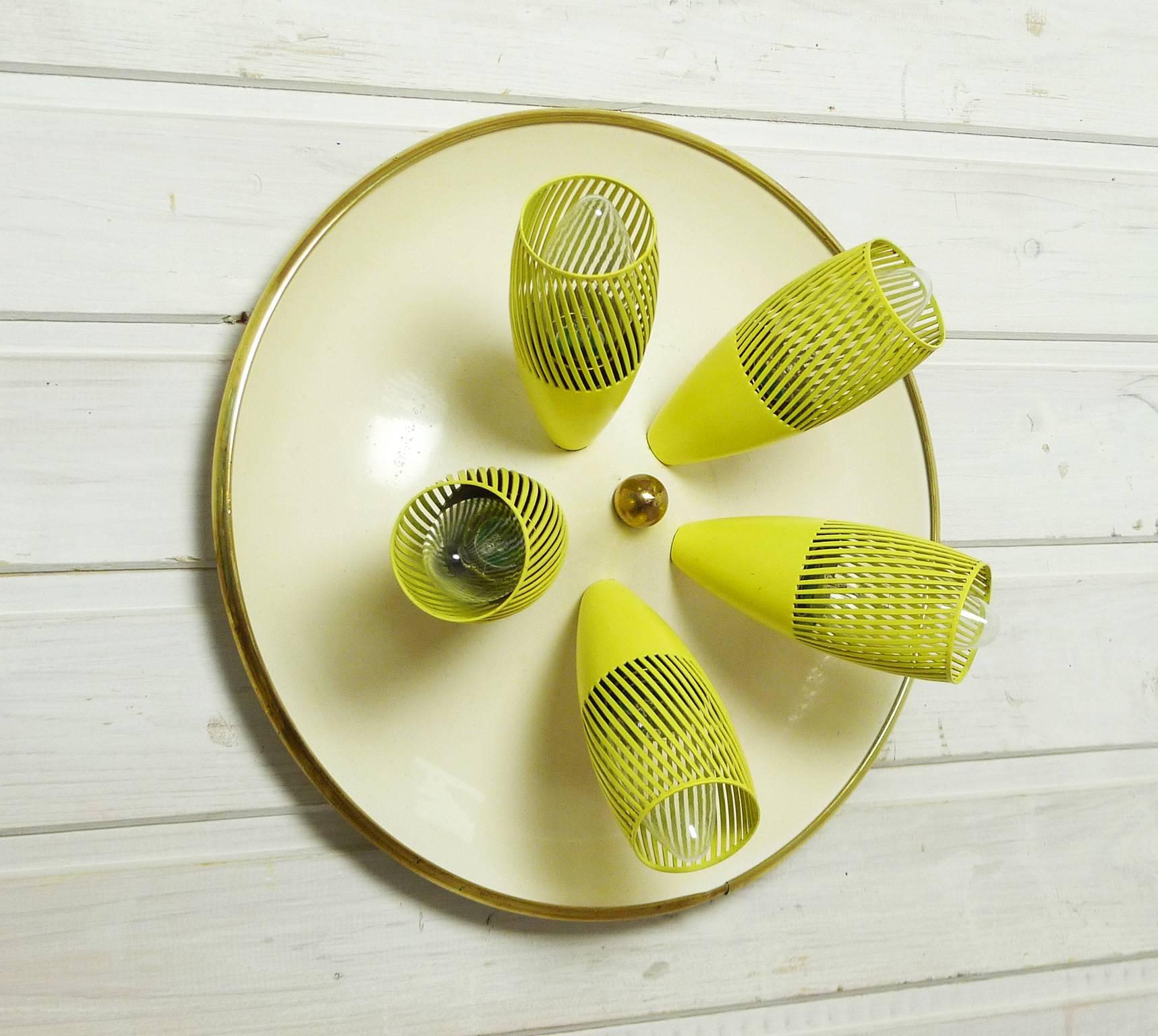Rare ceiling lamp or sconce with five E 14 bulb holders inside yellow lacquered funnels with slits on a round beige plate with a brass edge. The slotted funnels create a beautiful striped shadow. This metal lamp is rewired for German standard. It is