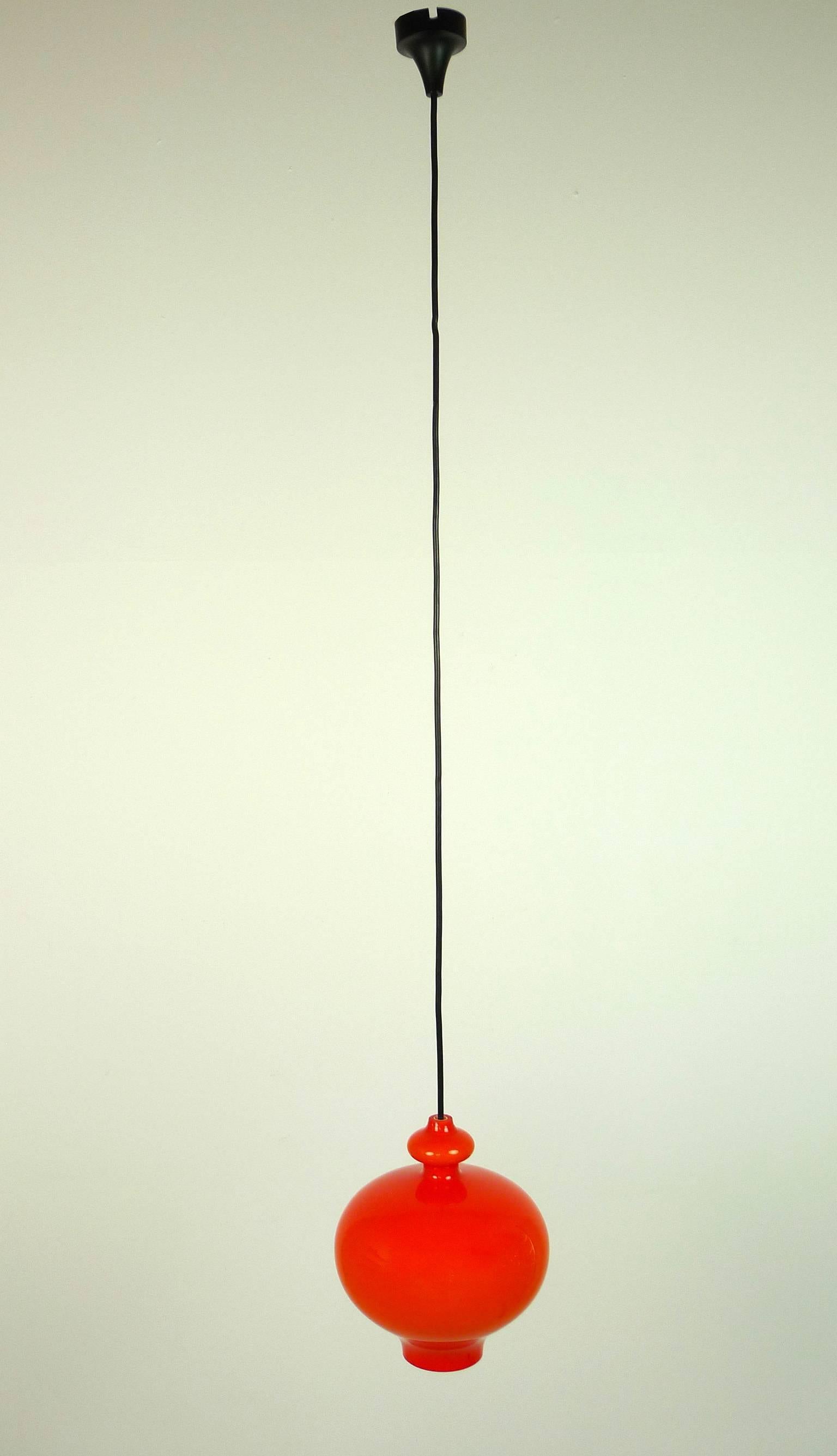 The orange onion body of the pendant lamp is made of handblown glass from Holmegaard and has one E 27 bulb holder inside. The lamp was produced by the German manufacturer Staff Leuchten in the 1960s. It is wired for German standard and in excellent