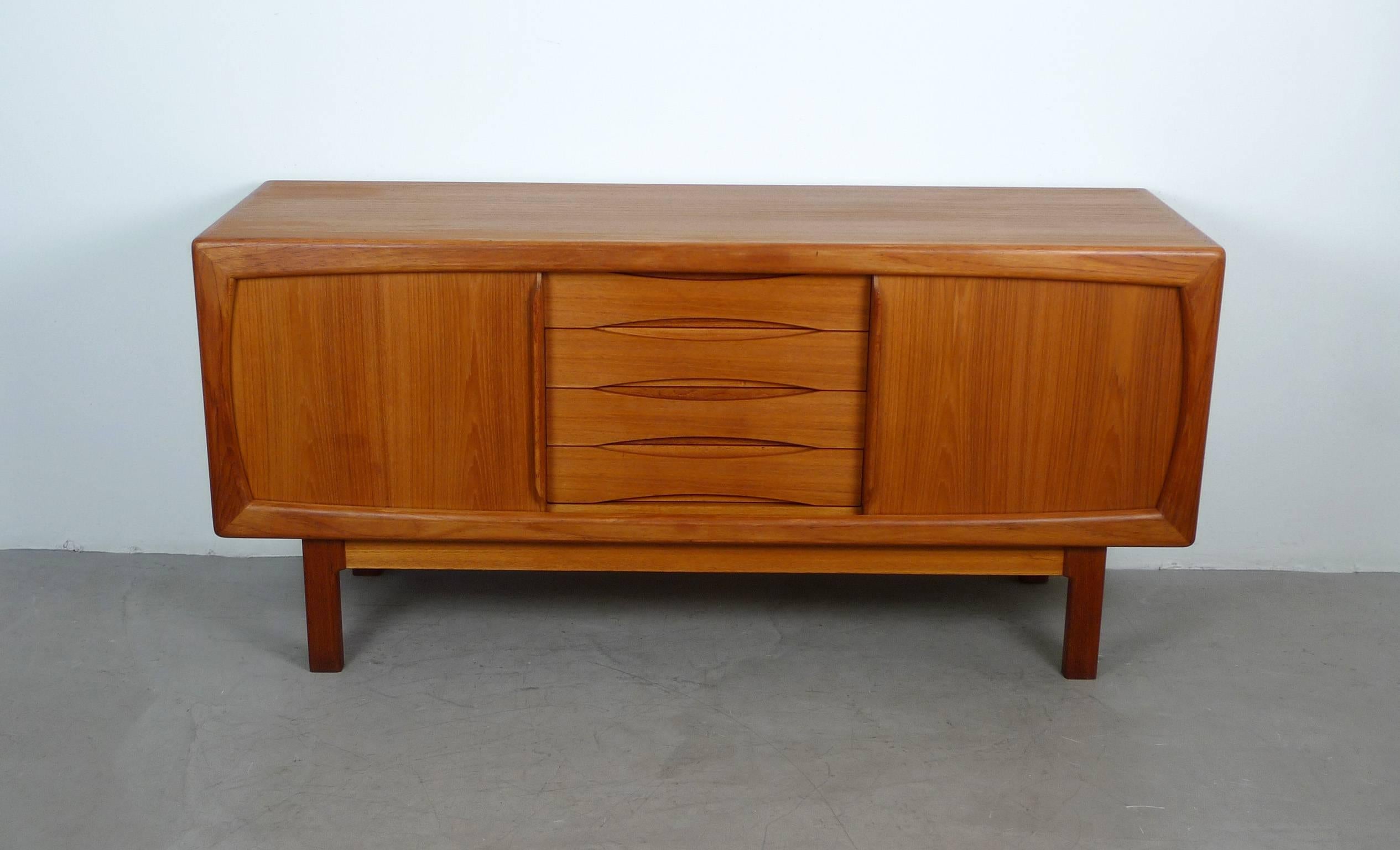 Teakwood sideboard with oval framed front, four drawers and two sliding doors from the 1960s. Behind each door is one board adjustable in height. Each drawer has an elegant recessed grip. The sideboard was produced by the Danish furniture maker