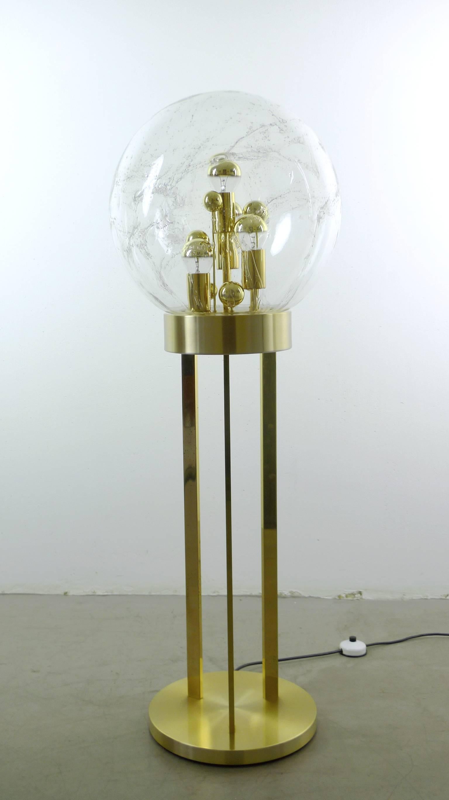 Rare golden floor lamp from the 1960s produced by the German manufacturer Doria.
Three bars holding a large glass globe with a diameter of 40 cm. Inside the globe several golden balls standing like mushrooms in varying heights. Four of them are