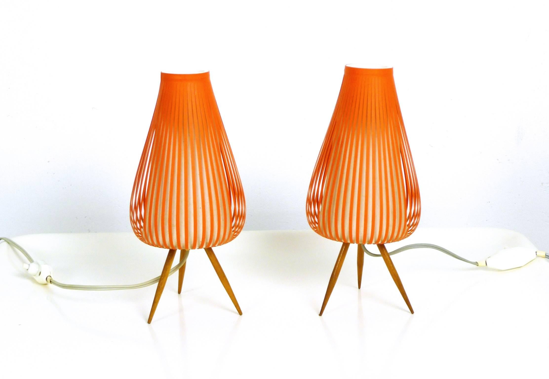This pair of table lamps for nightstands was made in Germany. The tripod bases are made of wood and the orange striped shades generate an interesting Silhouette of light and shadow. Both lamps are in a very good original condition.