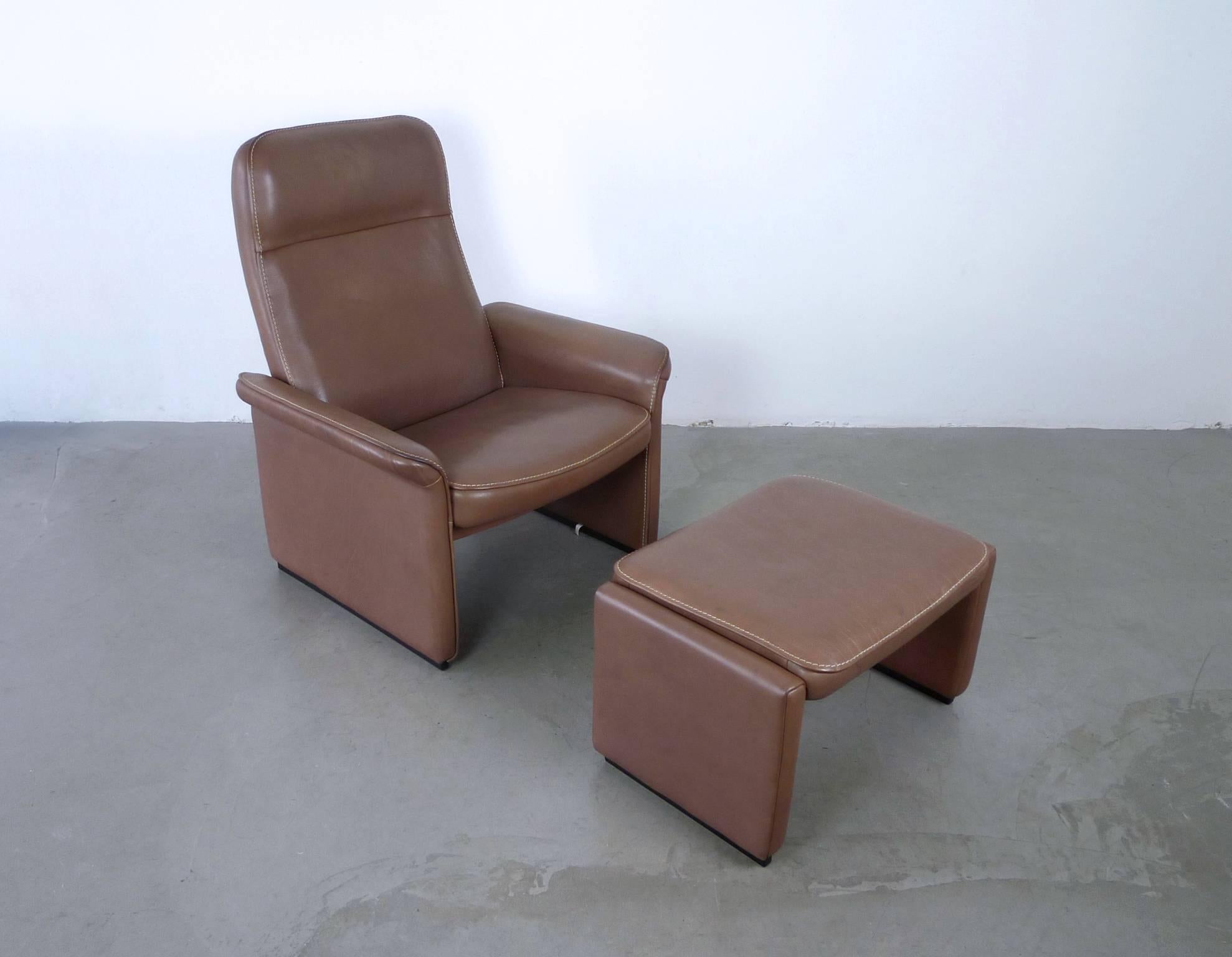 Model DS 50 lounge chair with matching ottoman from the Swiss manufacturer De Sede.
Chair and ottoman are upholstered in thick bright brown buffalo neck leather with black lacquered wood skids at the bottom.
The inclination angle of the backrest