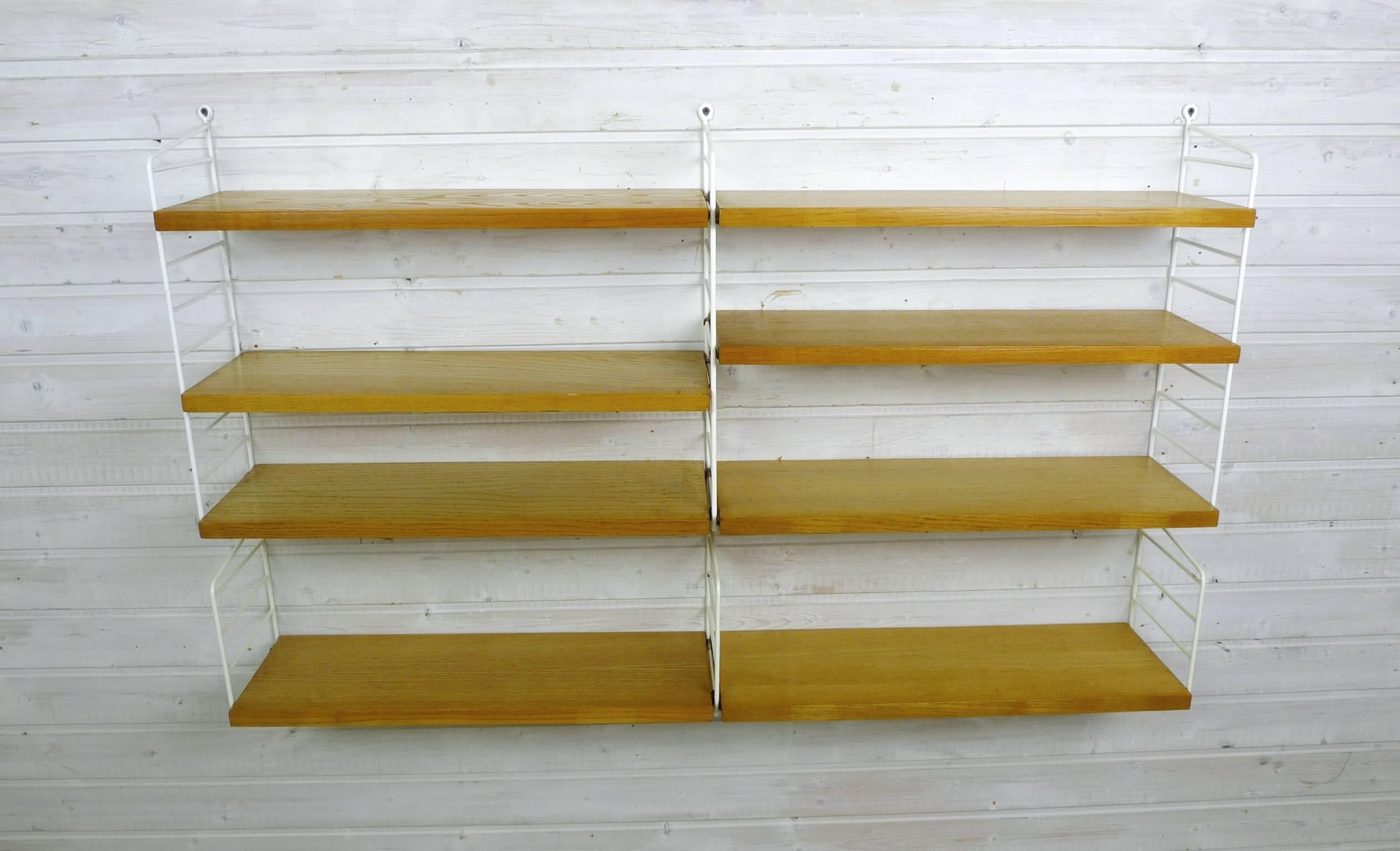 Nisse Strinning designed his famous shelf system in 1949, and it was produced in his own manufacturing company, String Design AB in Sweden.
This wall shelf consists of six white-coated ladders and eight shelves of ash, with a depth of 20 cm. The