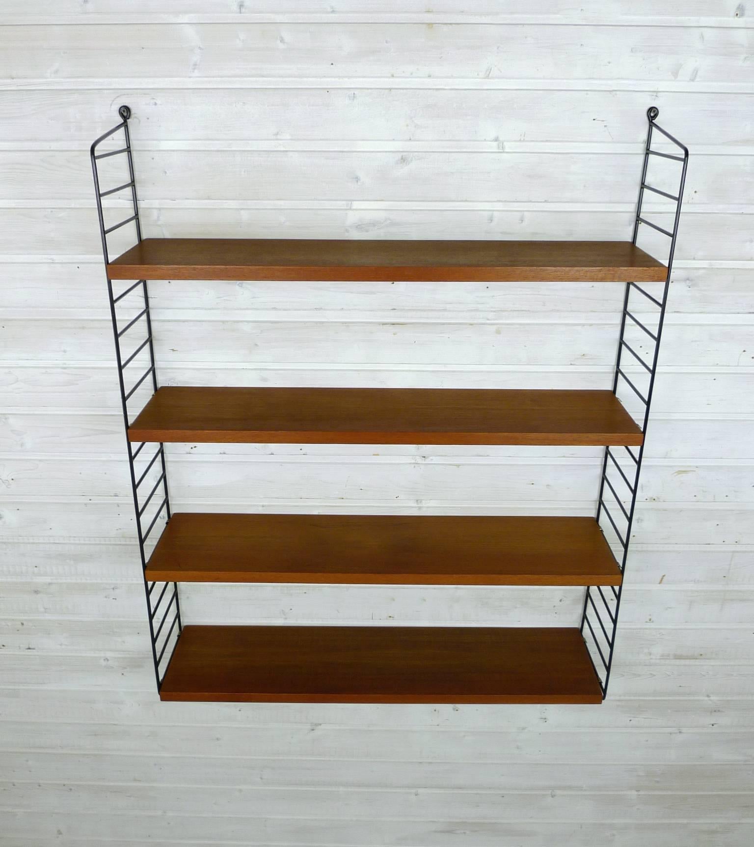 Nisse Strinning designed his famous shelf system in 1949. It was produced in his own company String Design AB in Sweden.
This wall shelf consists of two black-coated ladders and four shelves in teak with a depth of 20 cm. The shelf is in a good