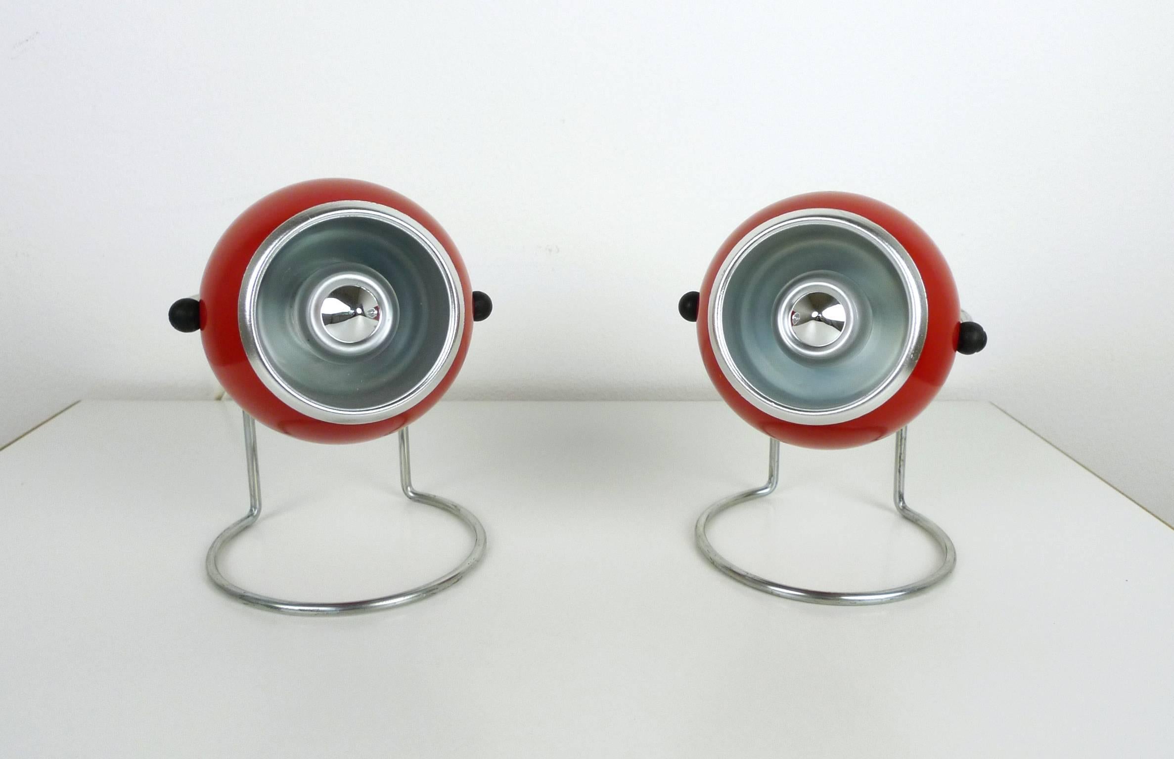 Two night lights with red lacquered metal balls on a chromed bracket made in the 1960s.
Two small black rubber bobbins connect the ball to the stand and allowing vertical rotation around the center axis. Inside there is an E 14 mount.