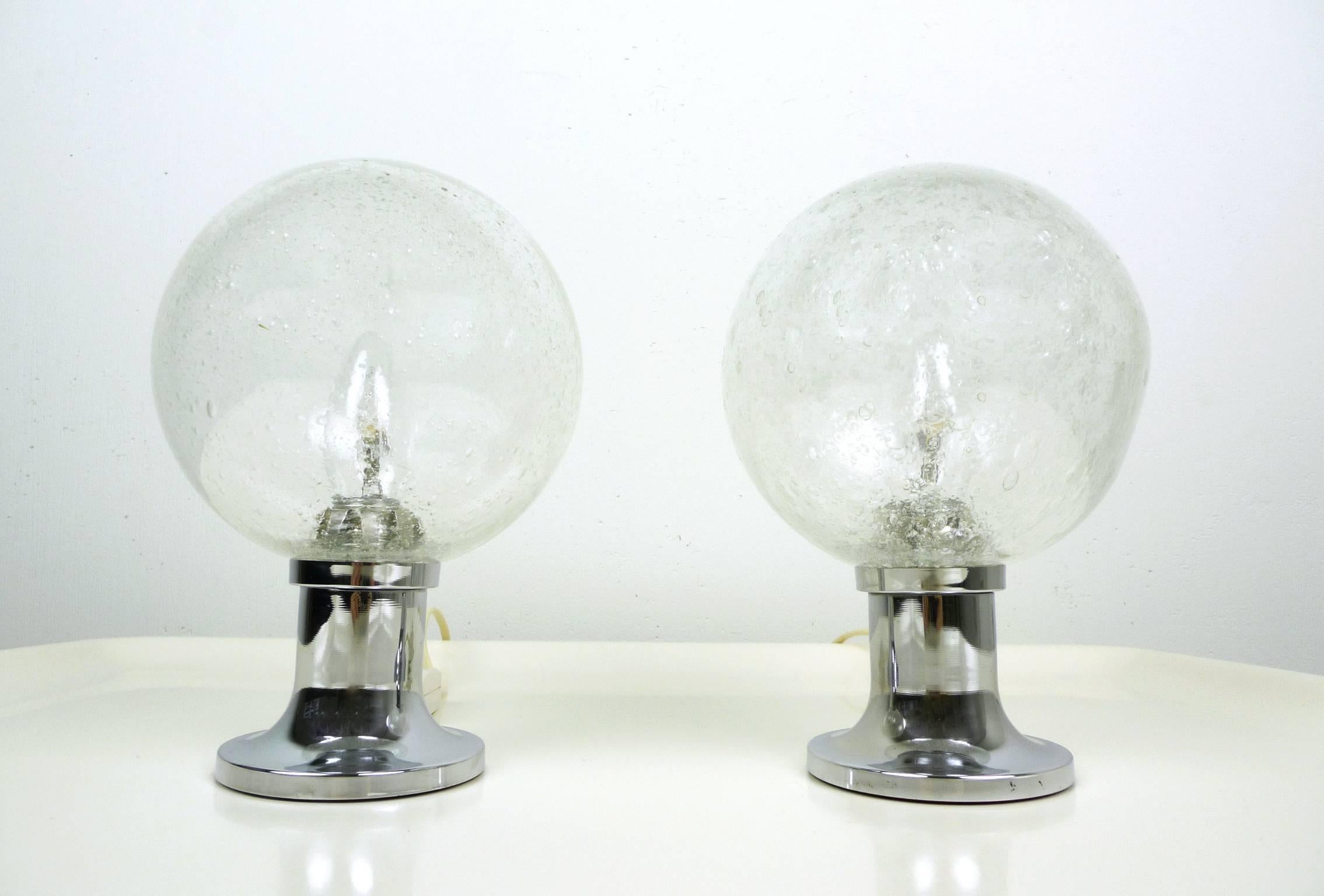 This pair of small table lamps has bubble glass globes and trumpet-shaped metal stands. It was designed by Egon Hillebrand in the 1960s and was manufactured by his company Hillebrand Leuchten in Germany. Both lights are in a very good original