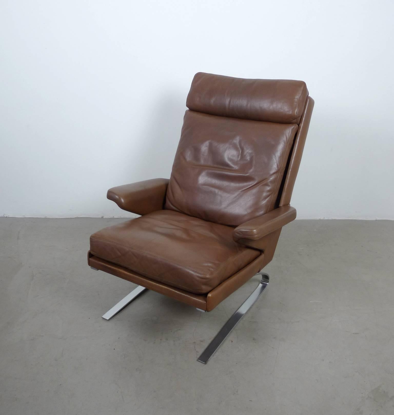 In 1968 Reinhold Adolf designed the model Swing chair for the German manufacturer COR. This version is upholstered in leather, with high backrest and armrests. The two skids are made of solid flat steel in the form of a sinusoid. It features a