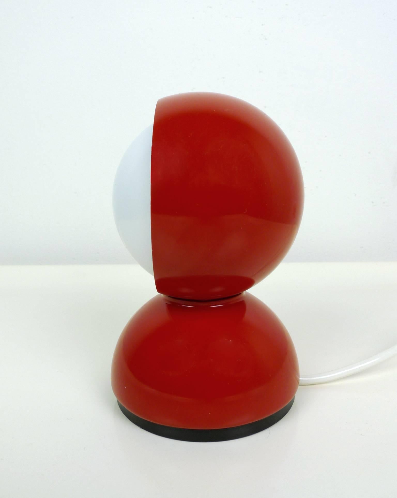 This Eclisse table or wall lamp was designed in 1967 by Vico Magistretti and produced by Artemide in Italy. The red-painted metal body surrounds a white hemisphere, which regulates the light intensity. The effect of the light is modeled on the moon