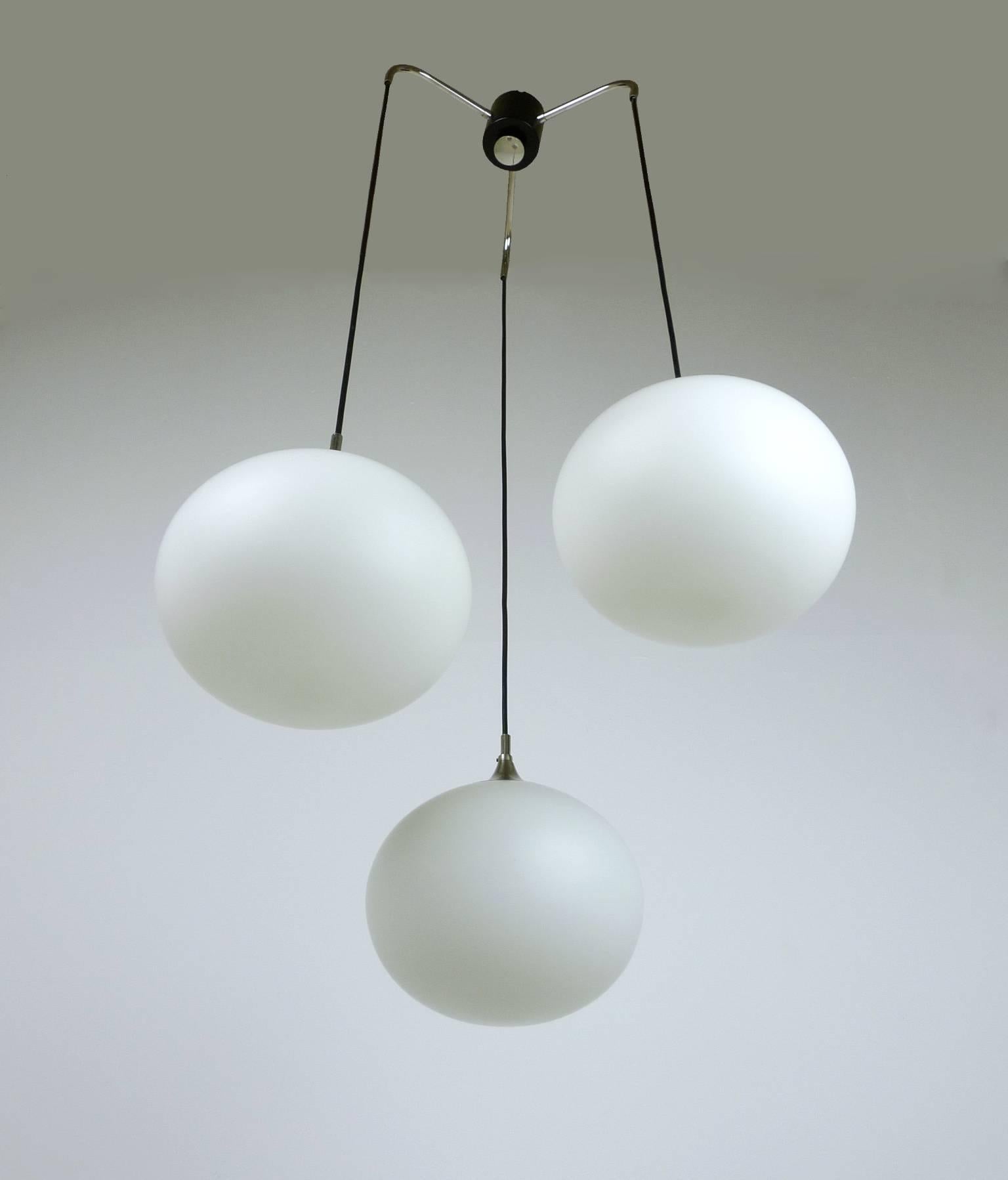 Cascade pendant with three opaline glass spheres from the German manufacturer Peill & Putzler. Each ball is crowned by a metal hood in the shape of a trumpet and has an E 27 socket inside. The lamp is in good vintage condition.