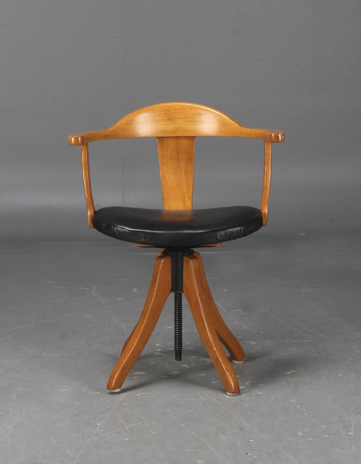 Danish Mid-Century swivel desk chair in solid oak with later upholstered in black leather. Spin mechanics in iron. Adjustable in height.