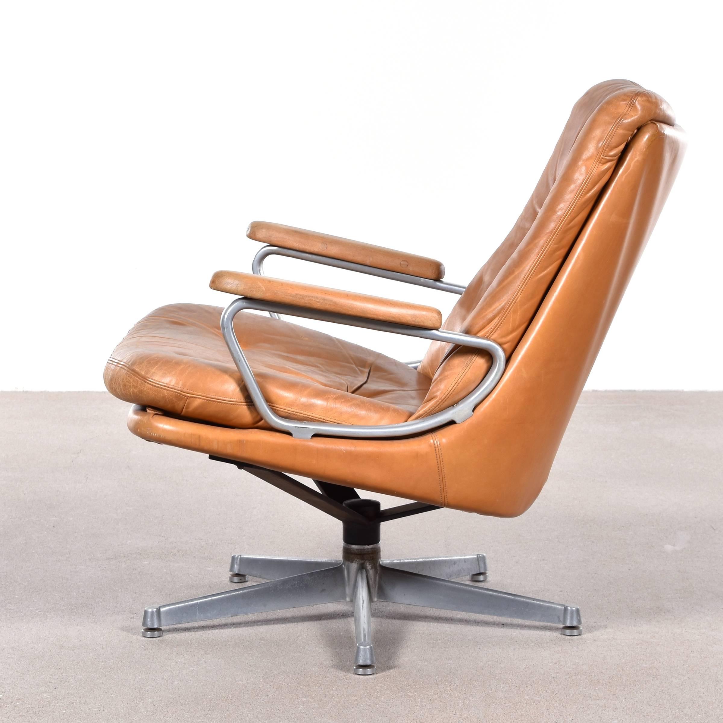 Comfortable swivel lounge chair by Andre Vandenbeuck for Strassle International. Heavy patina on cognac leather but still in god condition (Swiss quality). The leather can be restored or complete reupholstered if desired, please ask for