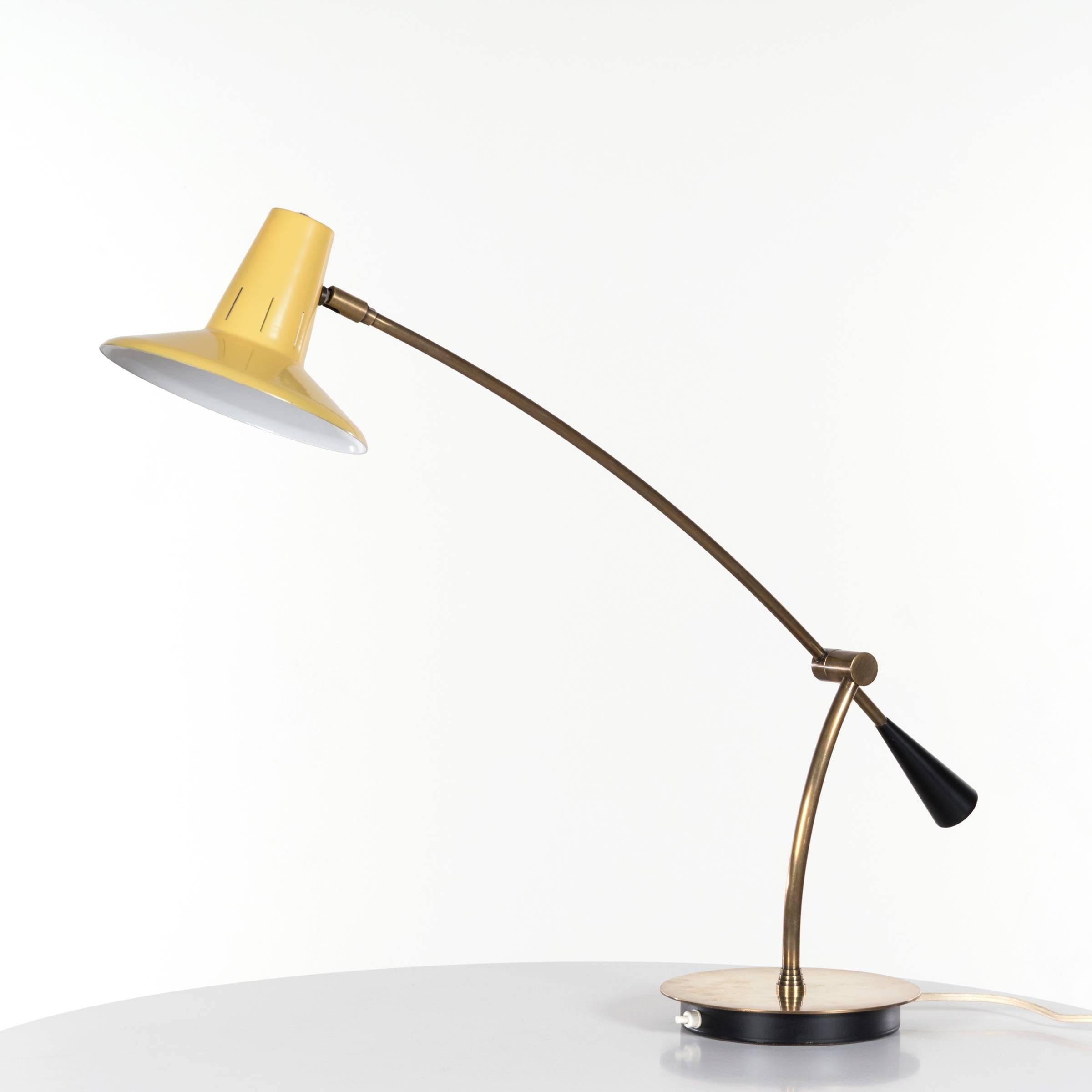 Elegant desk or table lamp by an unknown designer and manufacturer. Brass base with black accents adjustable in height and angle. Yellow enameled steel lamp cover. All in very good original condition.