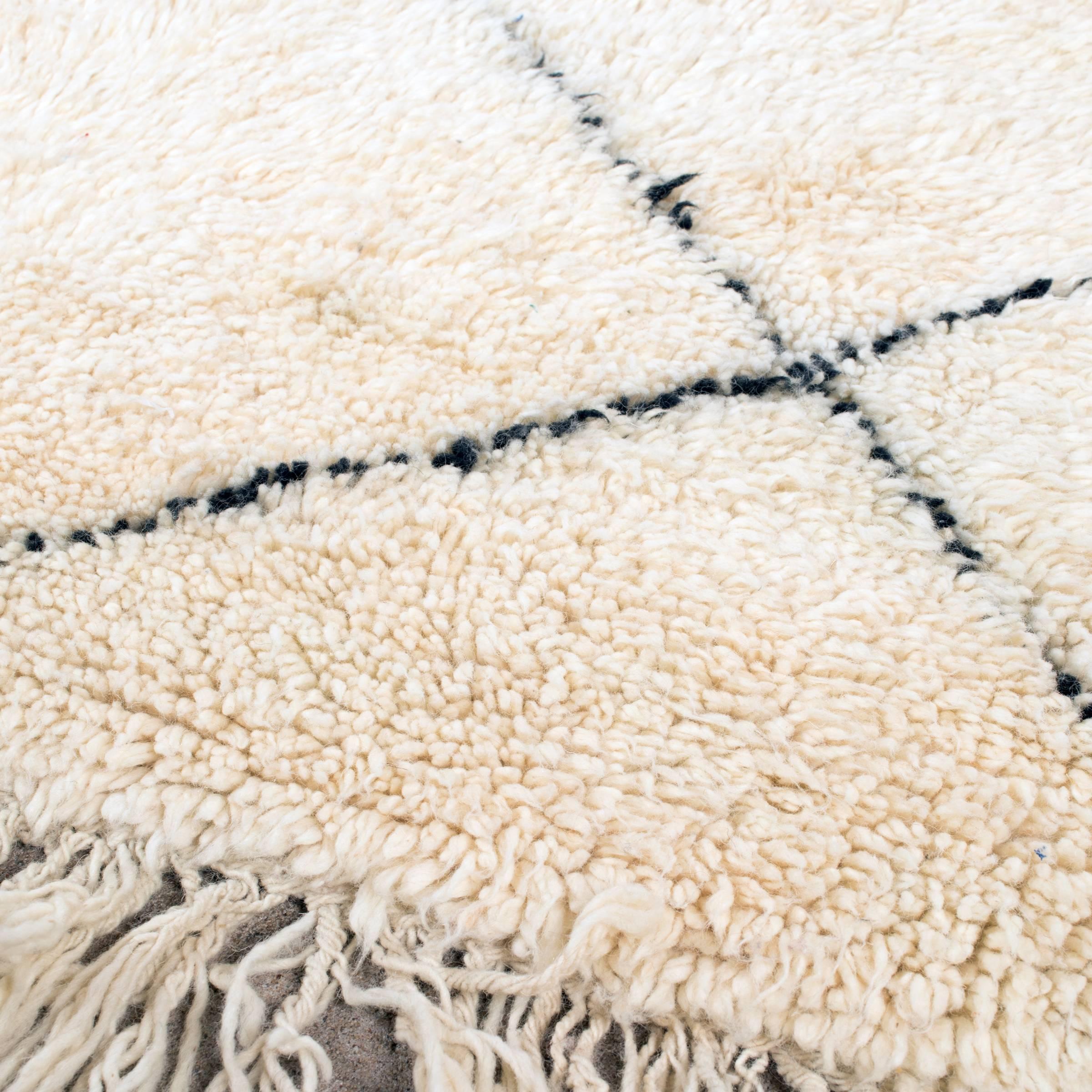 This vintage Beni Ouarain rug is carefully selected in Morocco and has a soft ivory color due to the wool's natural color and are accompanied by dark grey stripes. The rugs are named after the Berber village 'Beni Ouarain' in the mid-atlas mountain