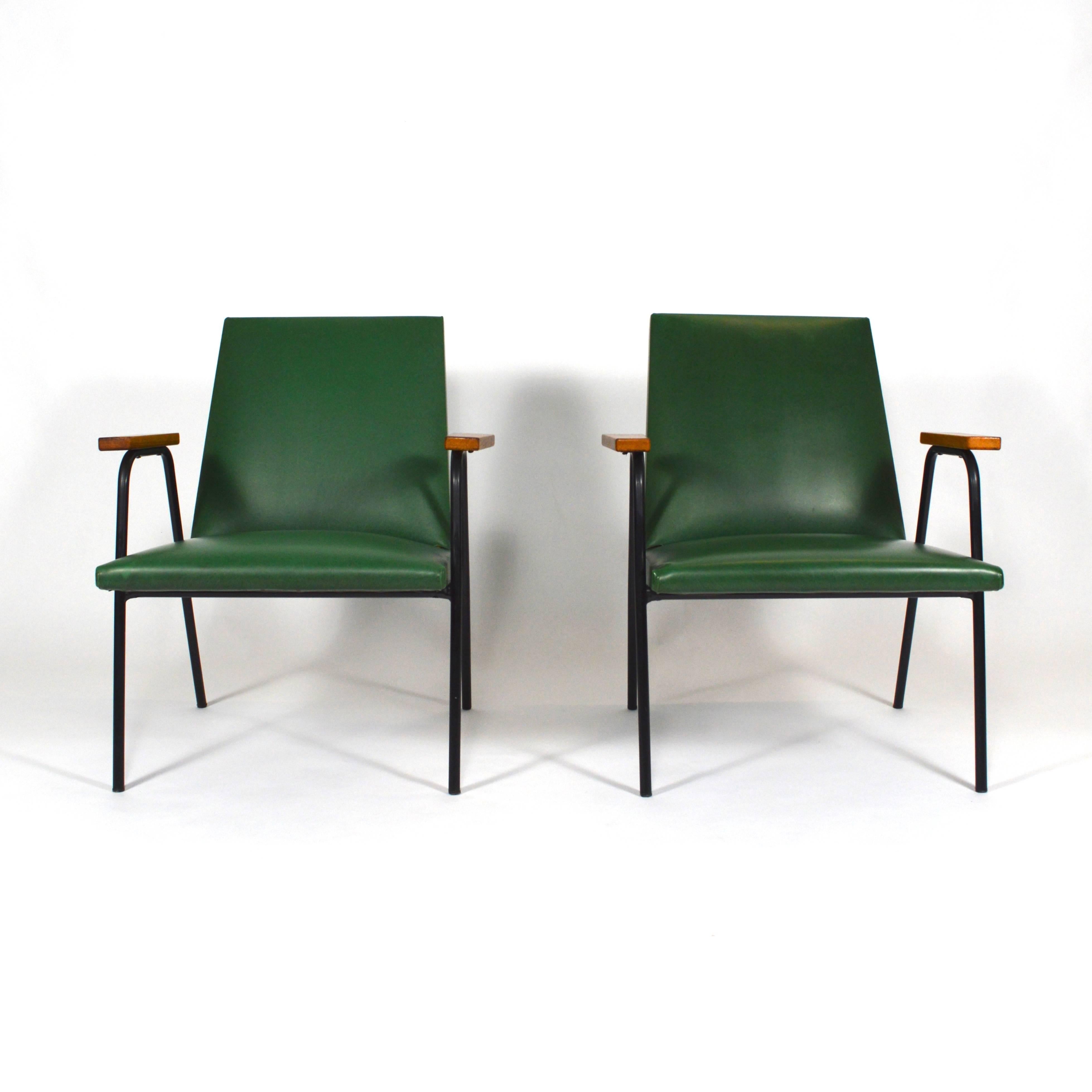 Very minimalistic but elegant pair of lounge chairs, France, 1950s-1960s. 
The armrests are made of solid birchwood, the frame is made of black lacquered metal and the upholstery is a very nice deep green faux leather.
The chairs are in original