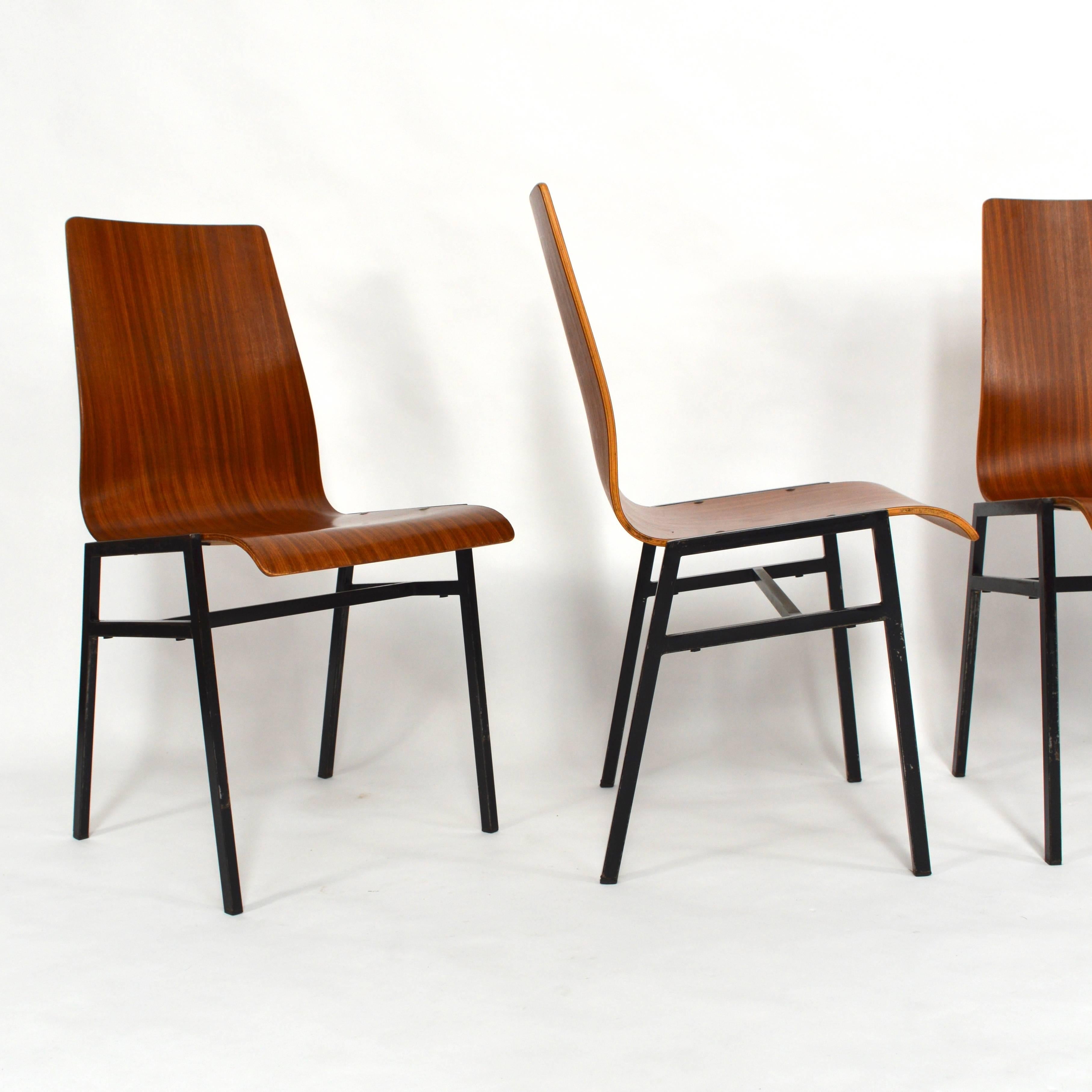 Sculptural teak plywood seats with black lacquered metal base.
The chairs are stackable.
In good condition with wear consistent with age and use.
