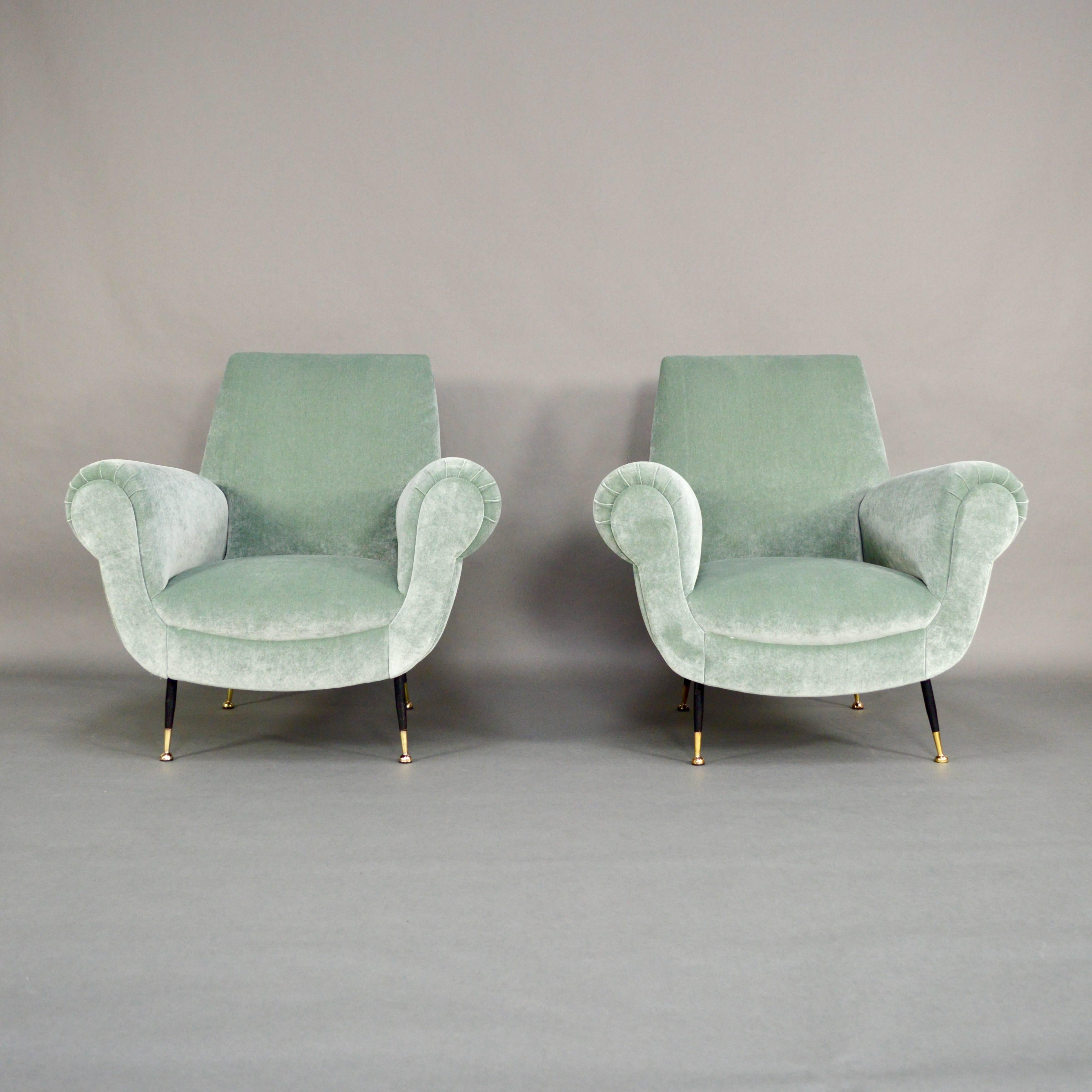 Iconic pair of club lounge chairs by Gigi Radice.
The chairs have been completely refurbished with new foam interior and a beautiful pastel green velvet fabric by JAB Urban Velvets.
The legs are made of brass and black lacquered metal. The brass
