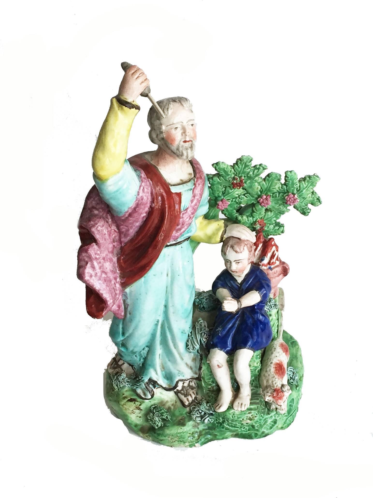 English Staffordshire pottery rare figure of Abraham offering to slay Isaac. The somber figure of Abraham wielding a knife on the left side of the ovular, low-mounded green base, with the figure of Isaac seated under a tree issuing bocage to his